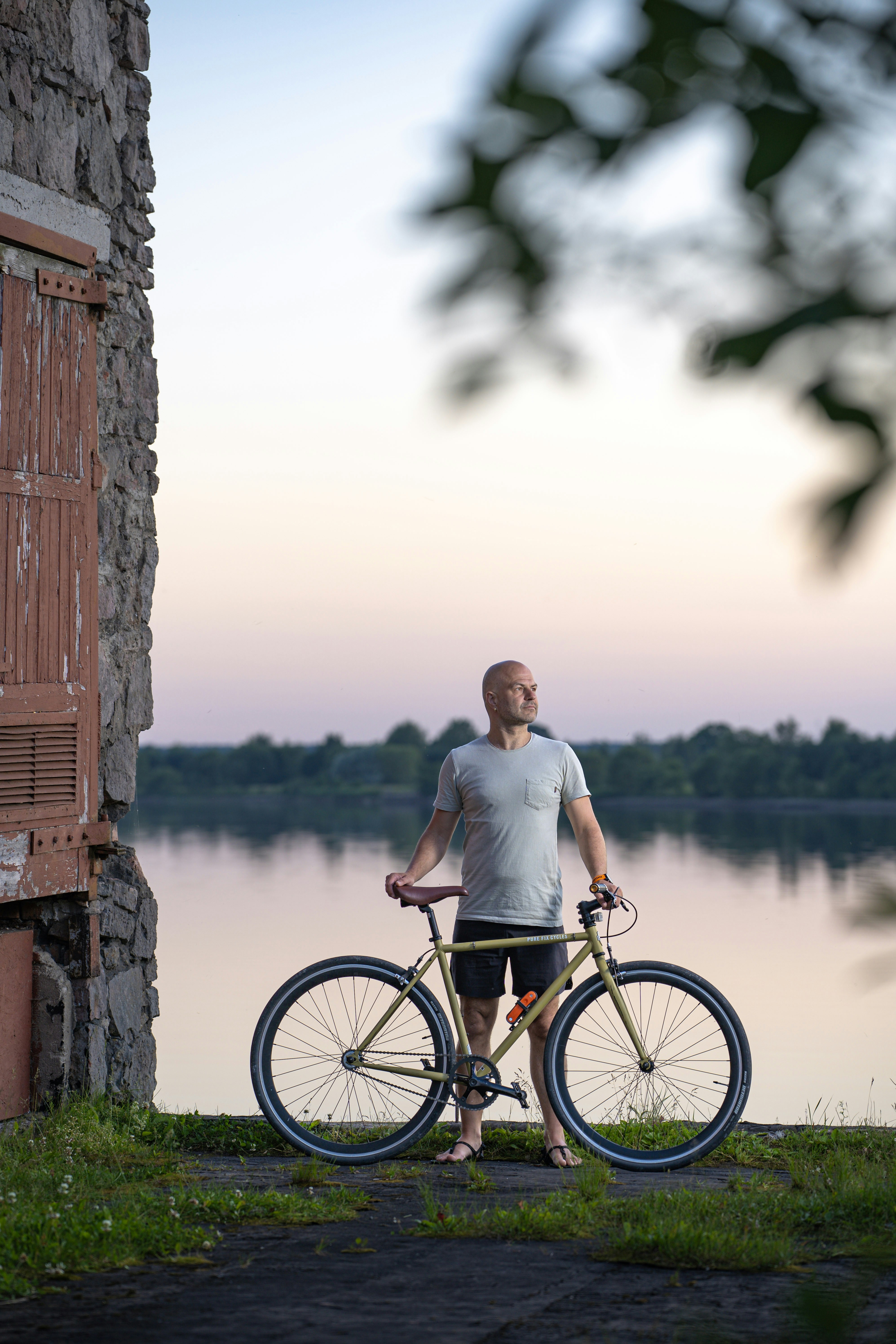 Man with bicycle by a calm lake at sunset