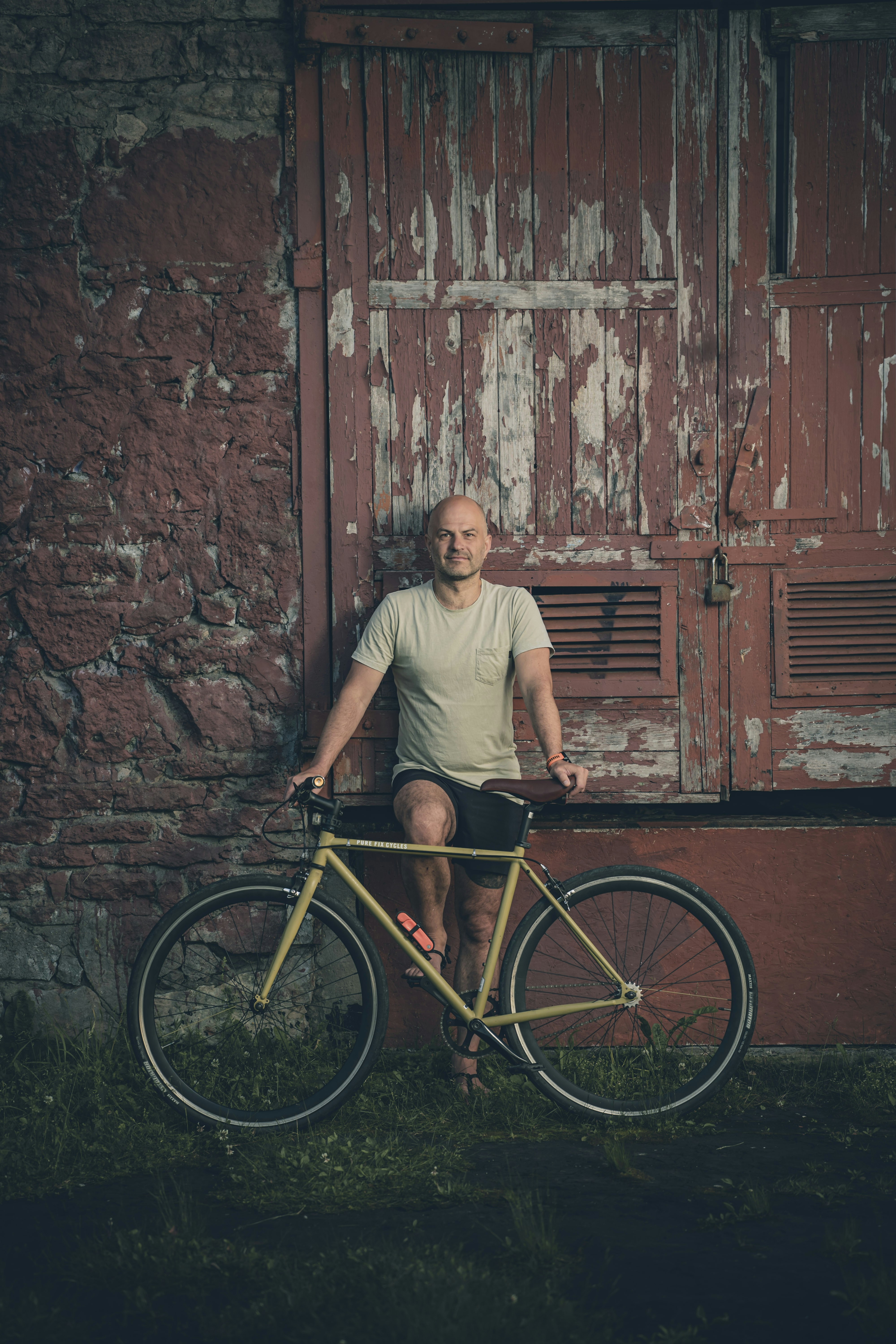 Man with bicycle leaning against weathered red door