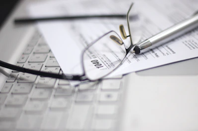 Glasses and pen on tax form and laptop.