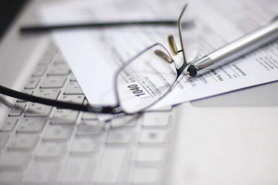 Glasses and pen on tax form and laptop.