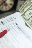 Tax forms with dollars and pencil