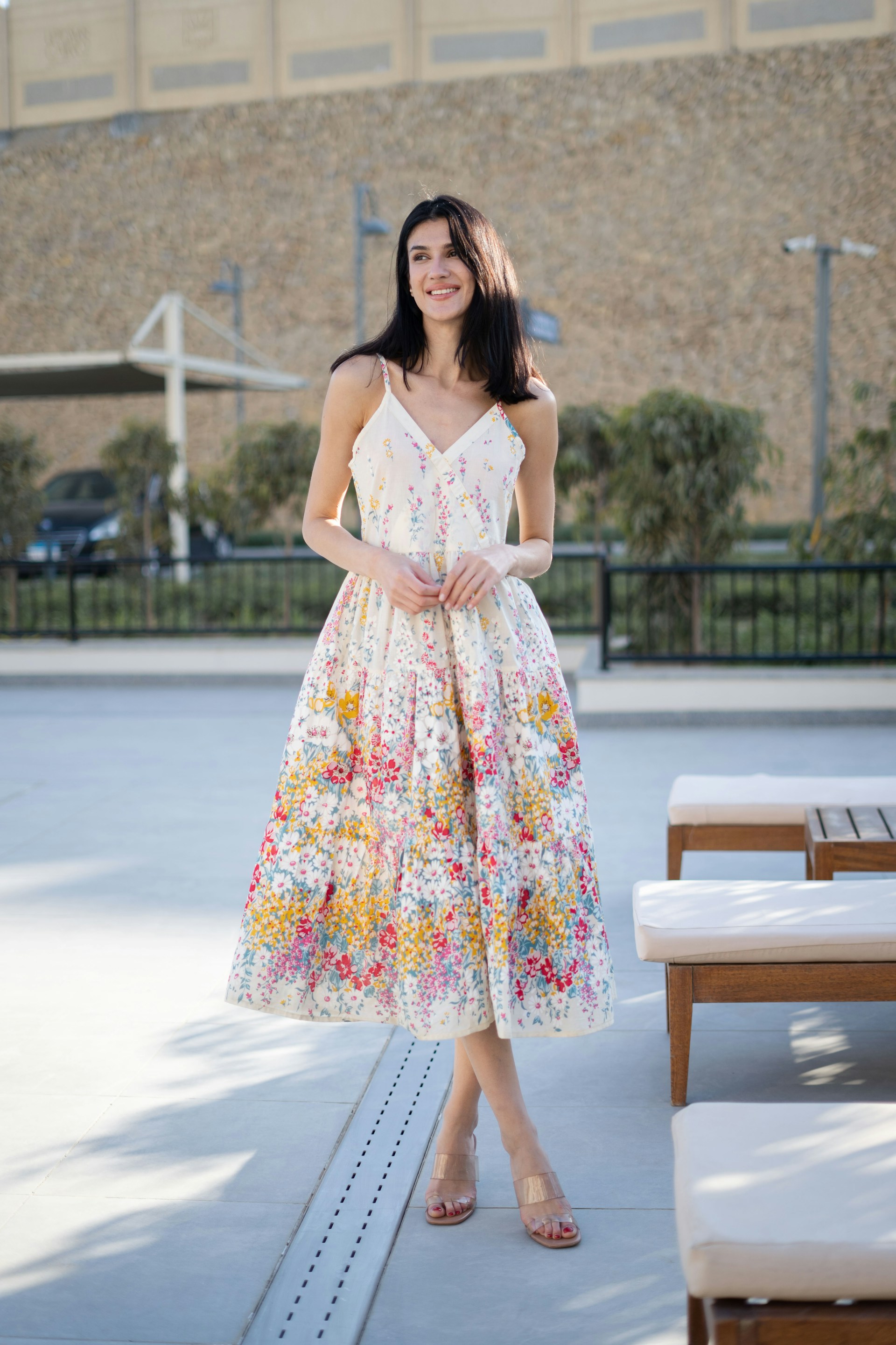 Woman in a floral sundress standing outdoors.