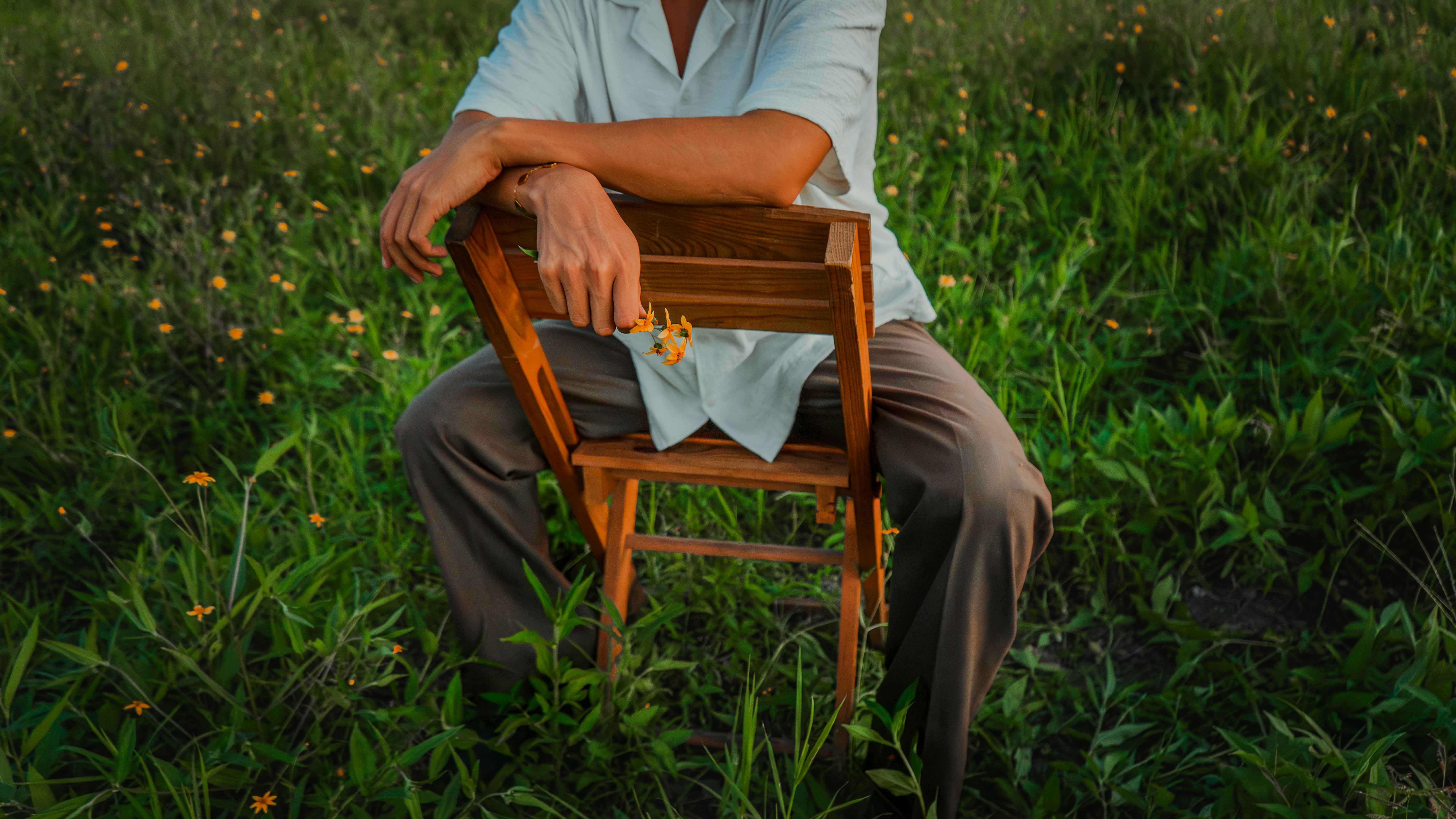 Man sitting on a wooden chair in a field.