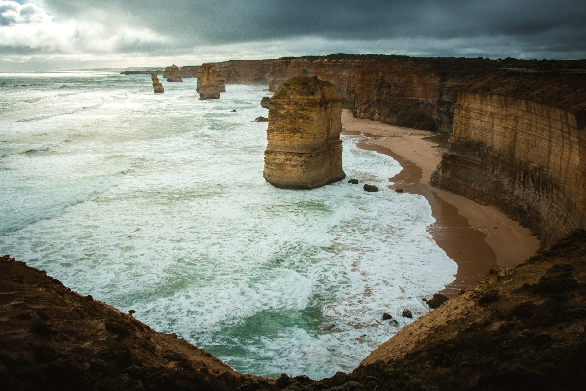Jagged rock formations rise from ocean waves near shore.