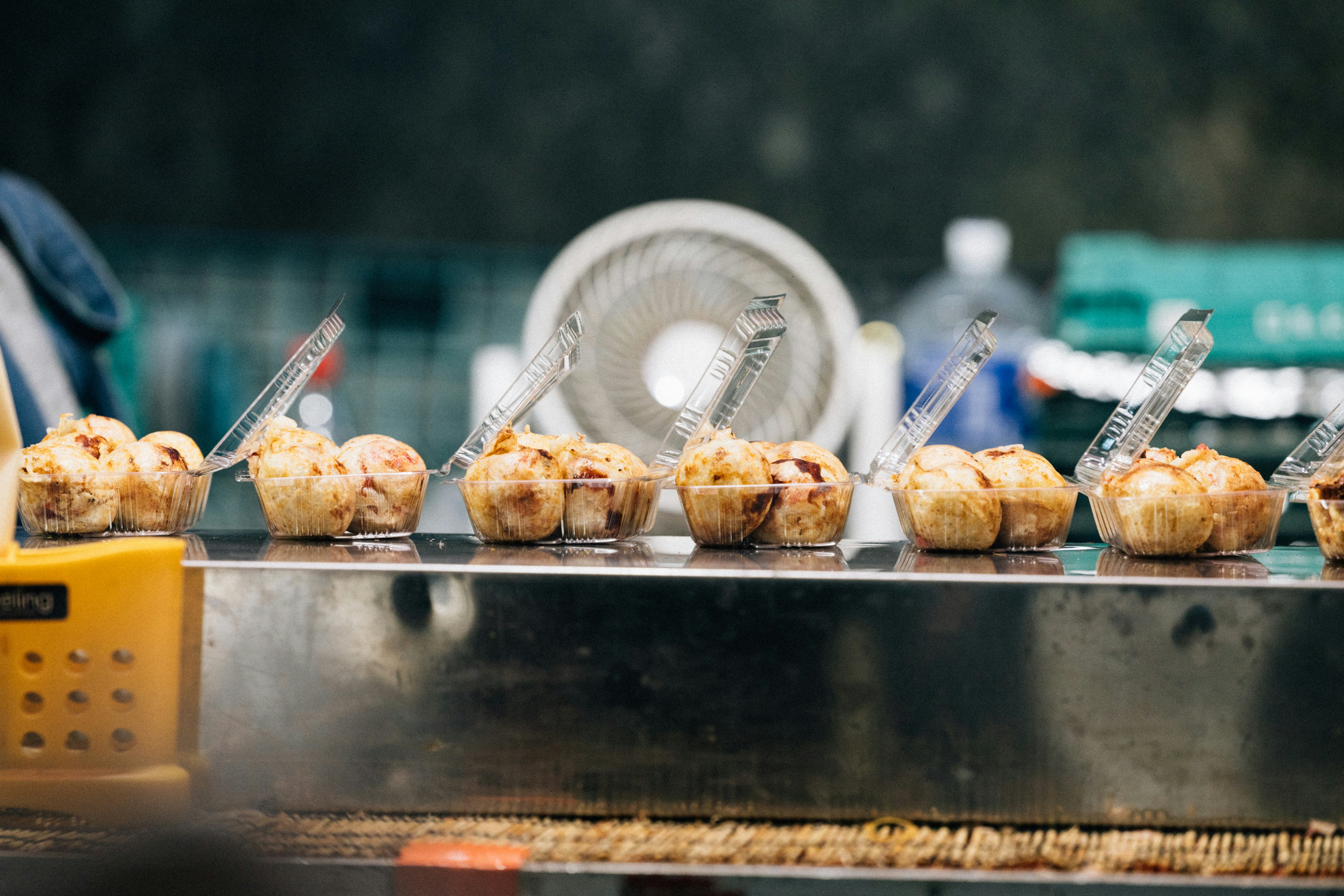Muffins displayed on a metal counter with tongs.