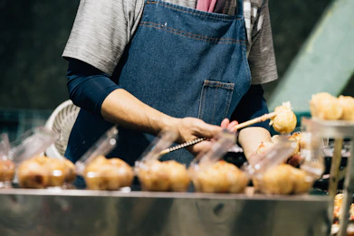 Person in apron preparing food on a stick