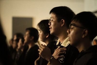 People with eyes closed, hands on chest, singing