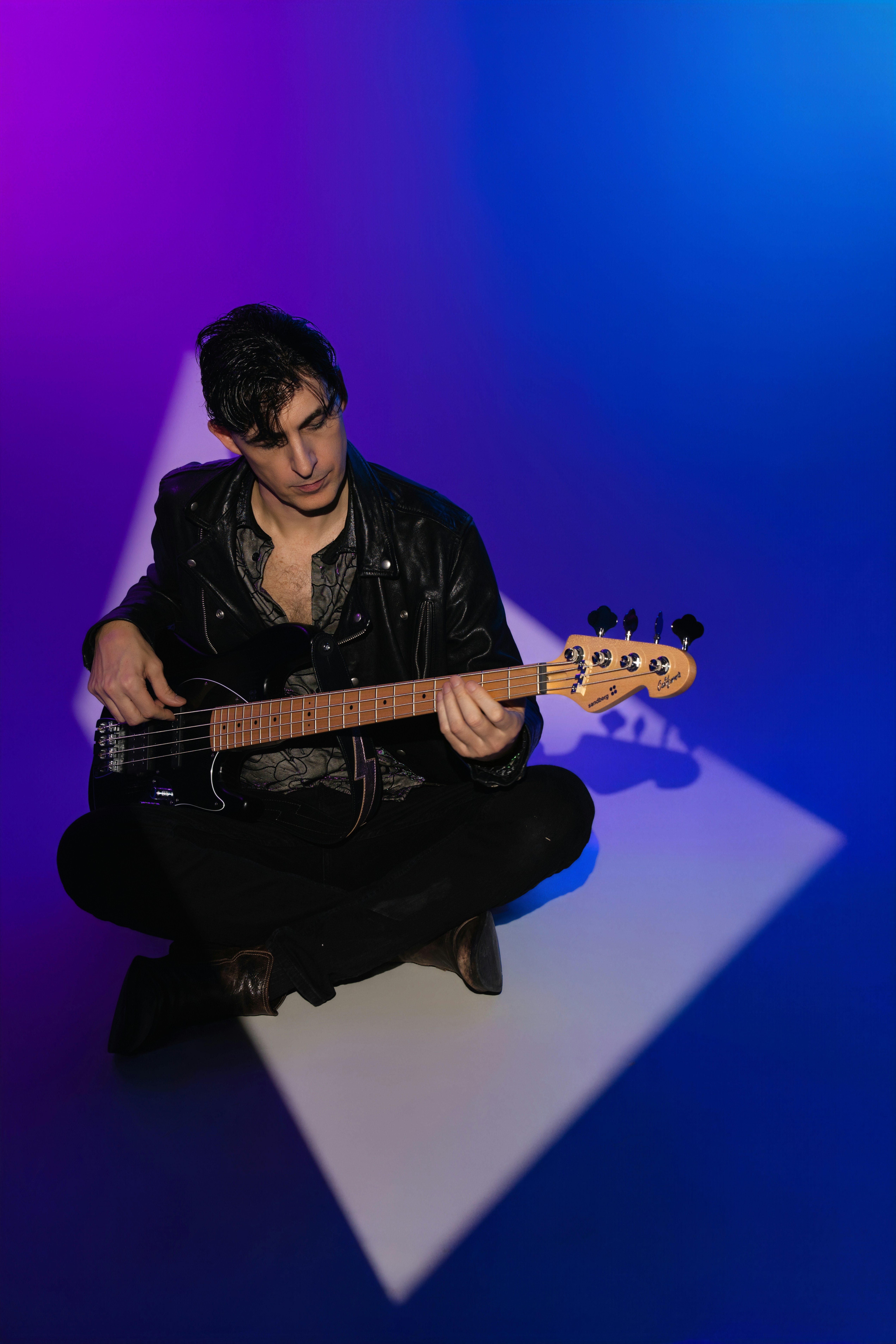 Man playing bass guitar with purple and blue lighting.