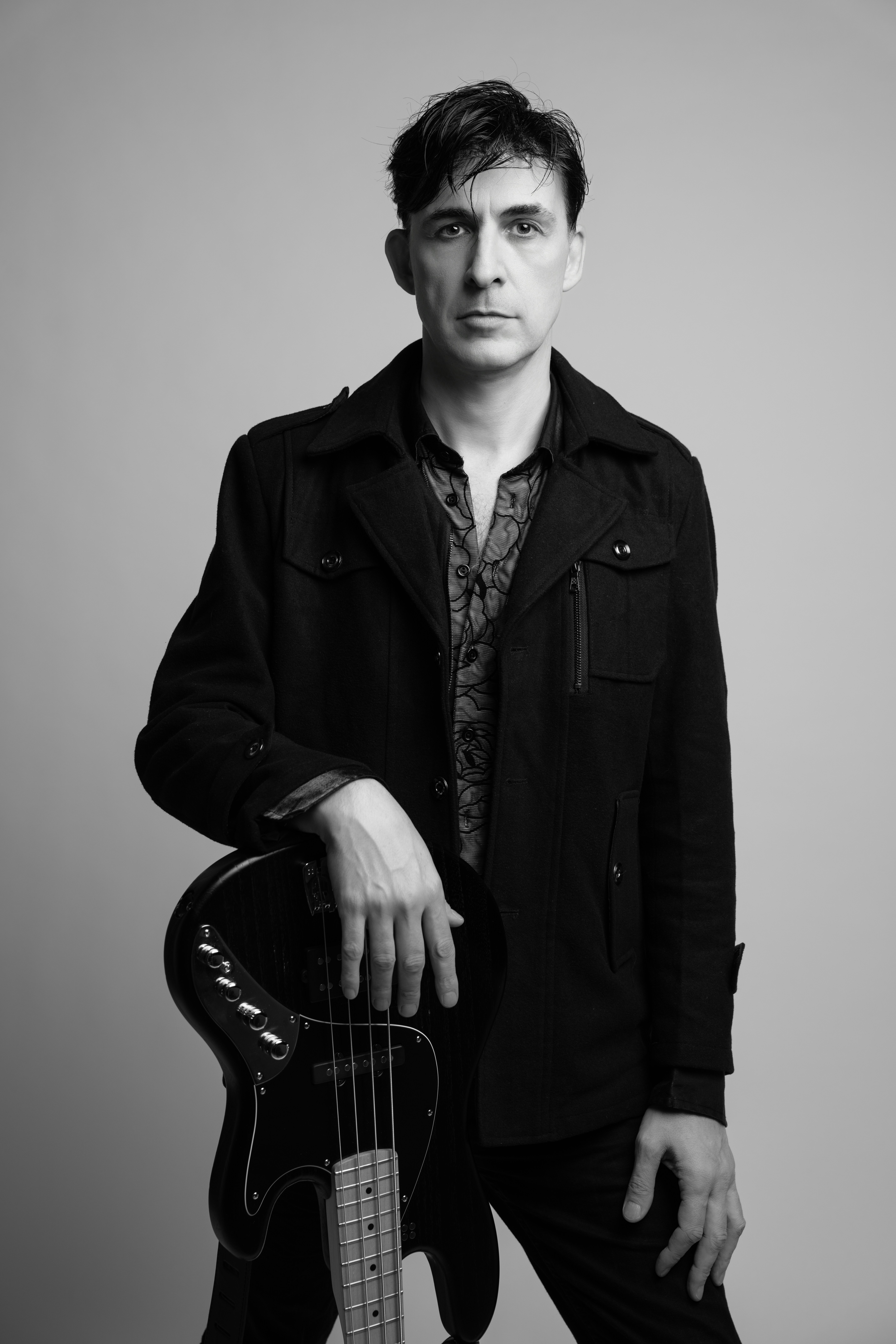 Man holding a bass guitar in black and white.