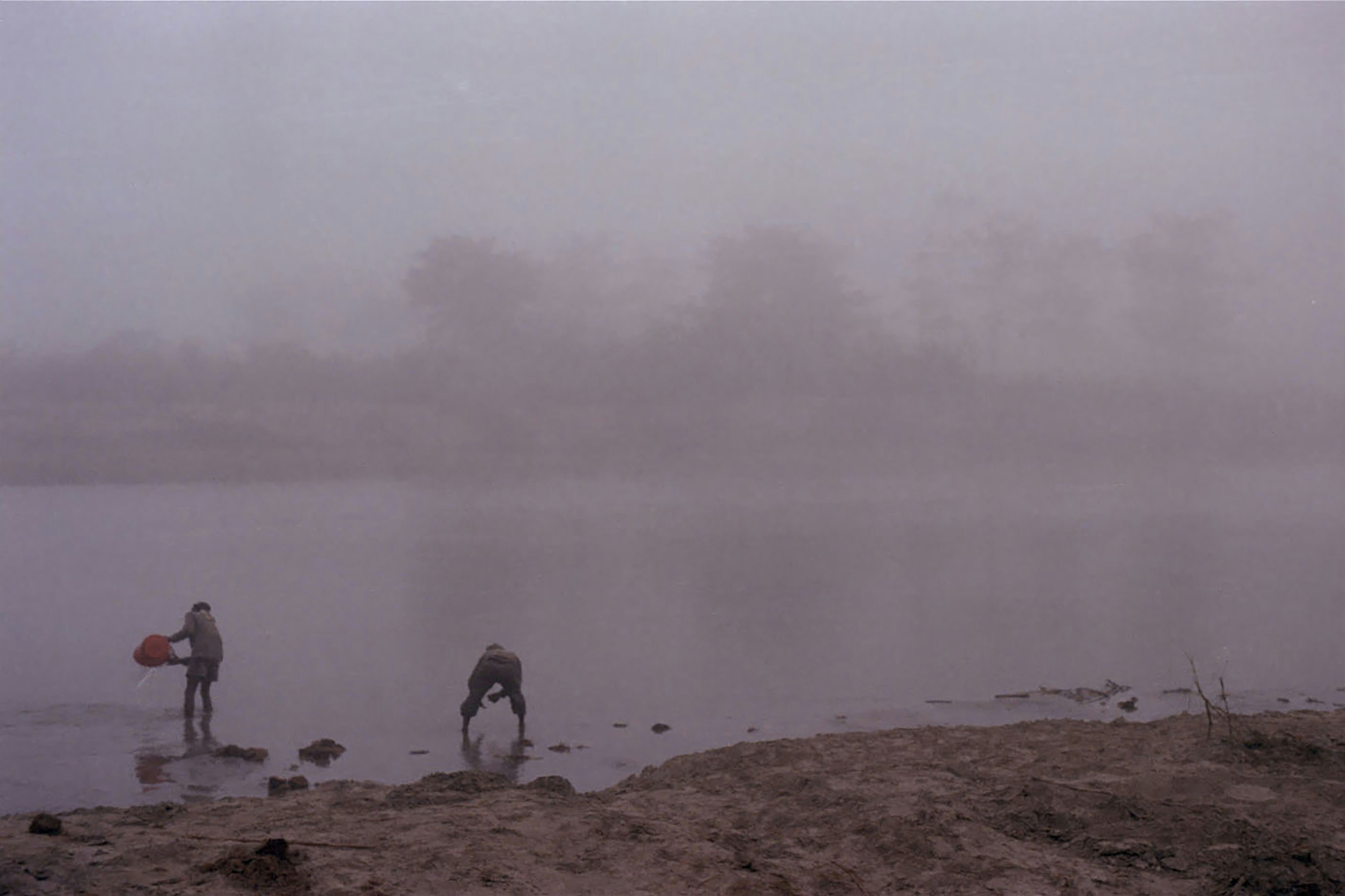 Two people by a foggy lake at dawn.