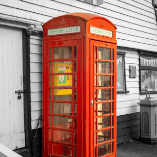 A red british telephone box with a defibrillator inside.