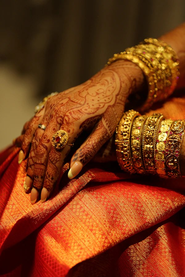 Hands adorned with mehendi and gold jewelry for a festive Puja