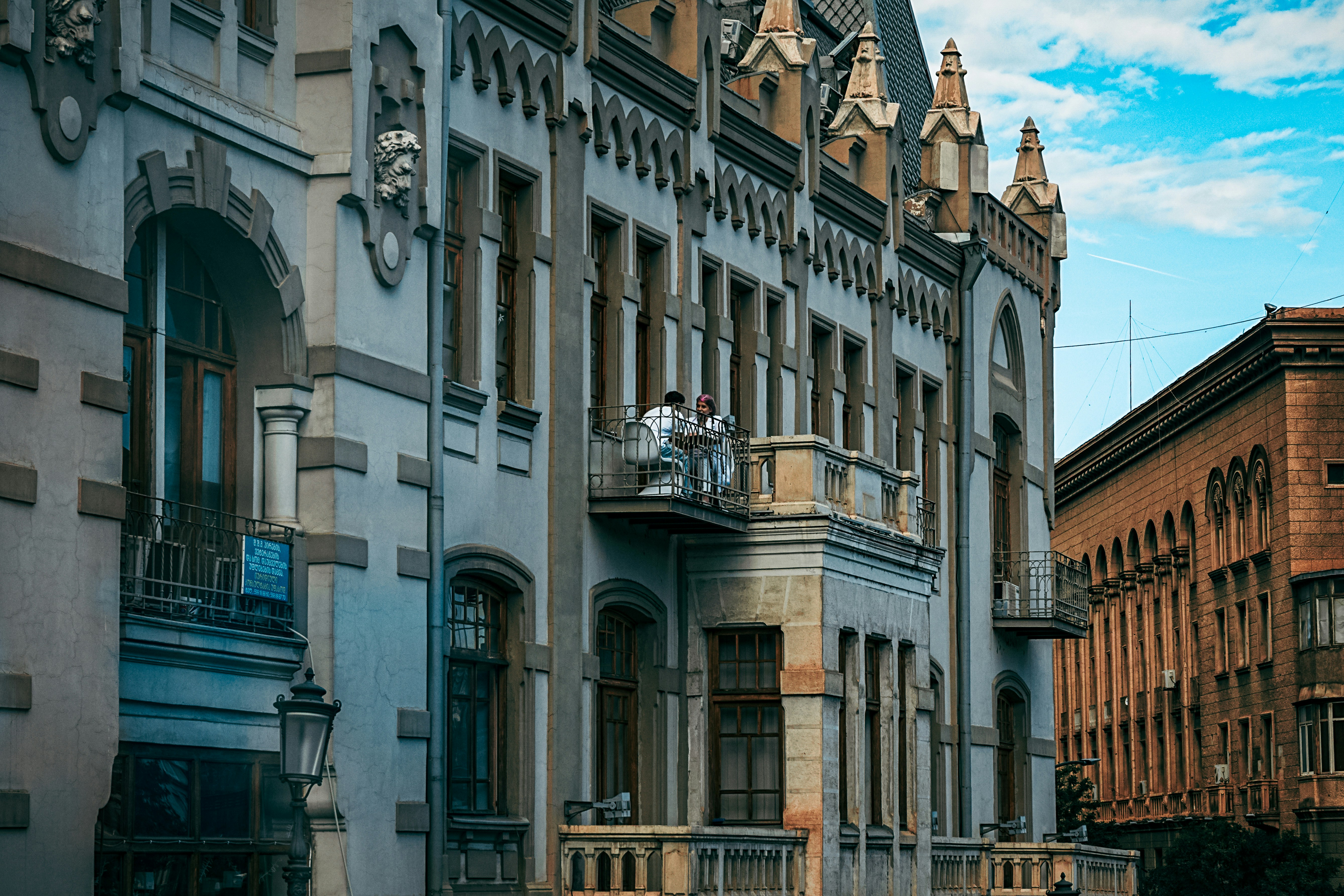 Two people on a balcony of an old building.