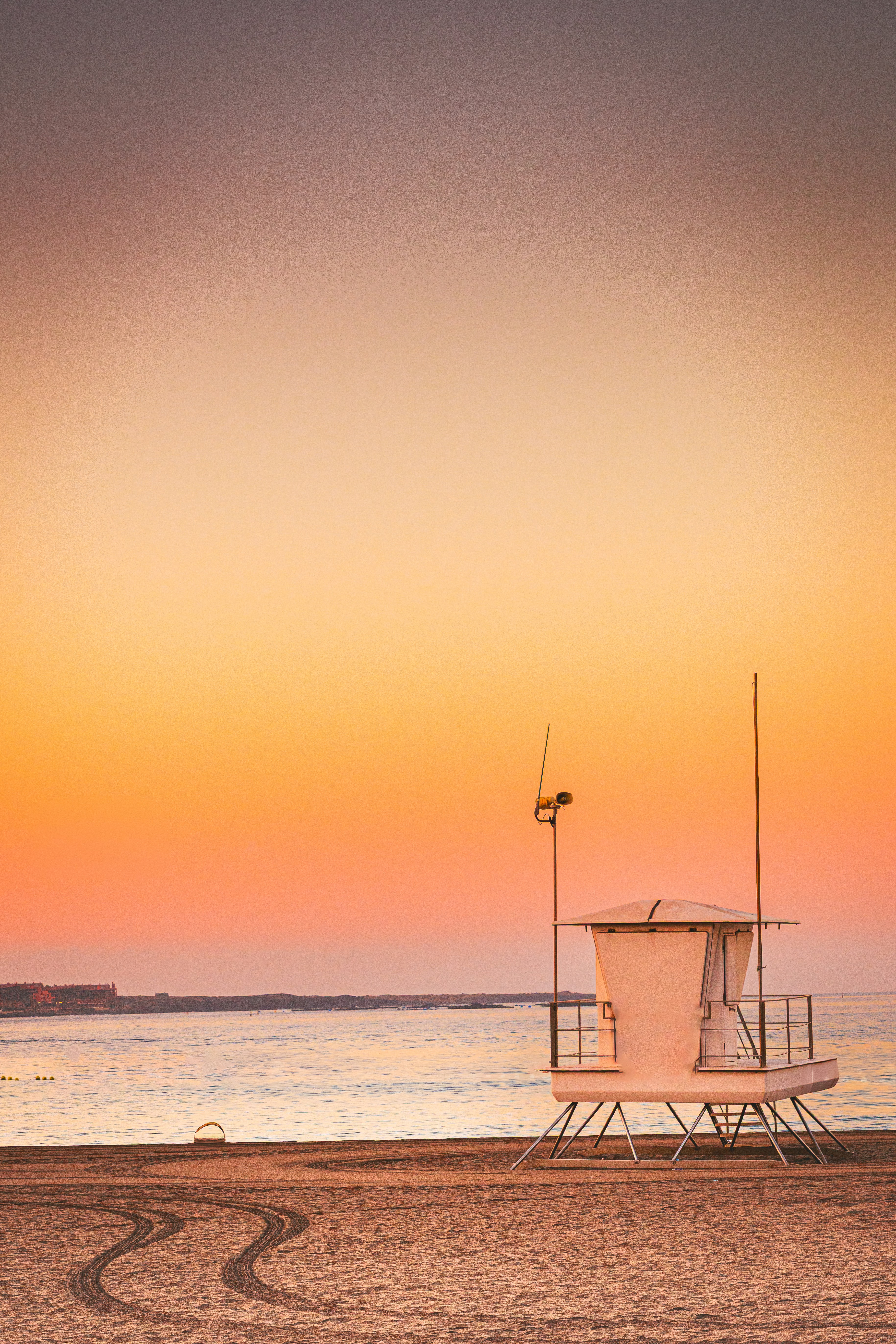 Menara penjaga pantai di pantai saat matahari terbenam.