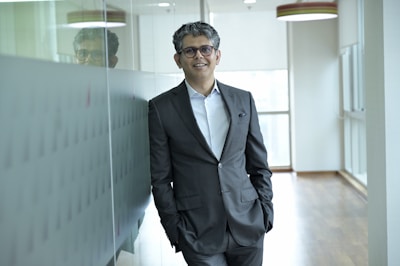 A man in a suit stands in an office hallway.