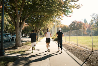Three people jogging on a sunny sidewalk