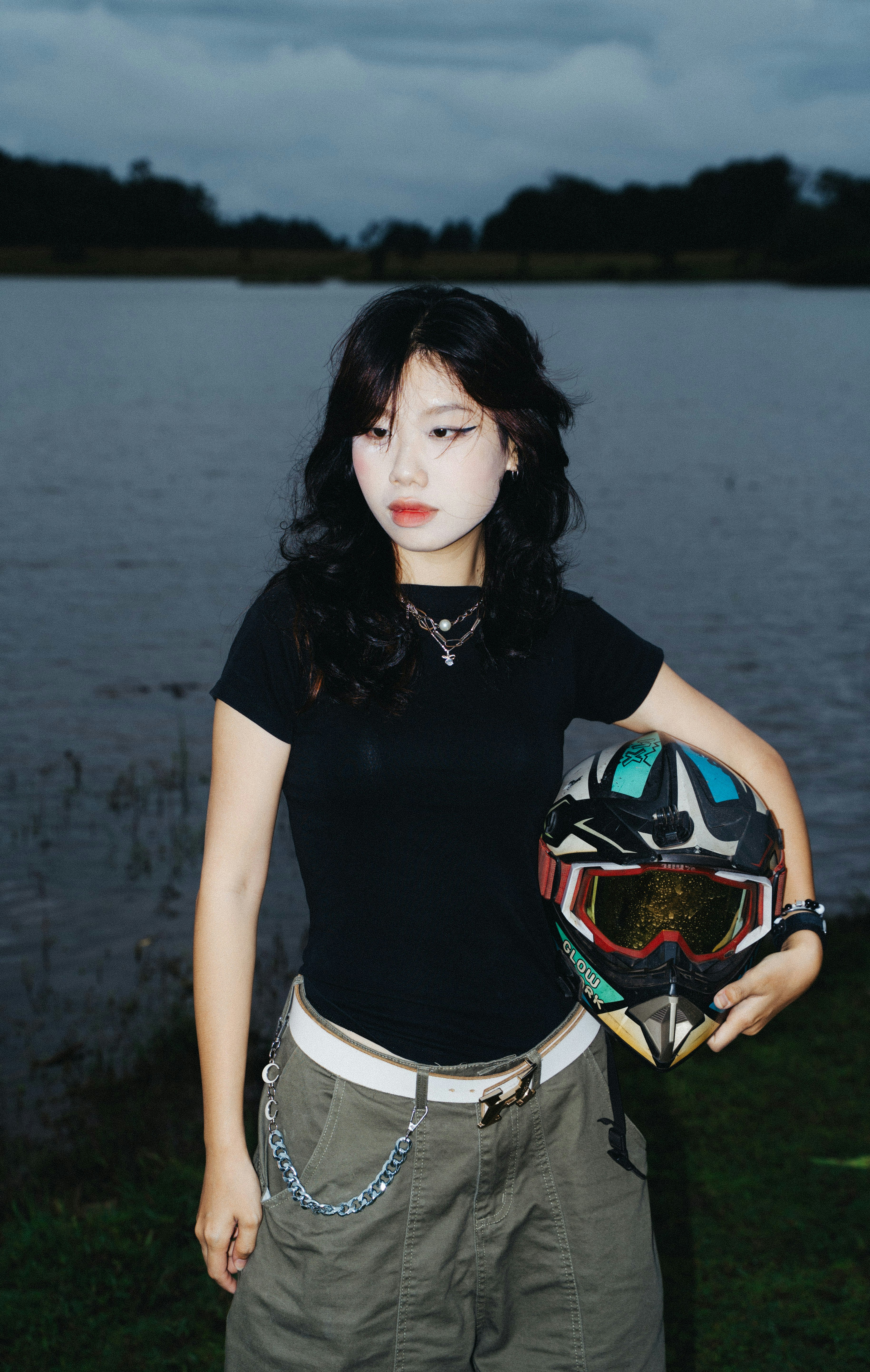 Young woman holding a colorful helmet by the water