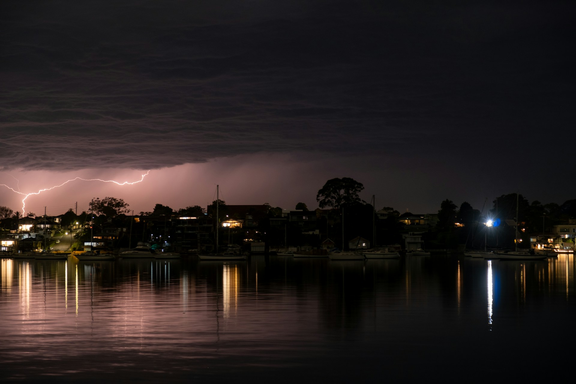 Lightning strikes over a dark cityscape at night.