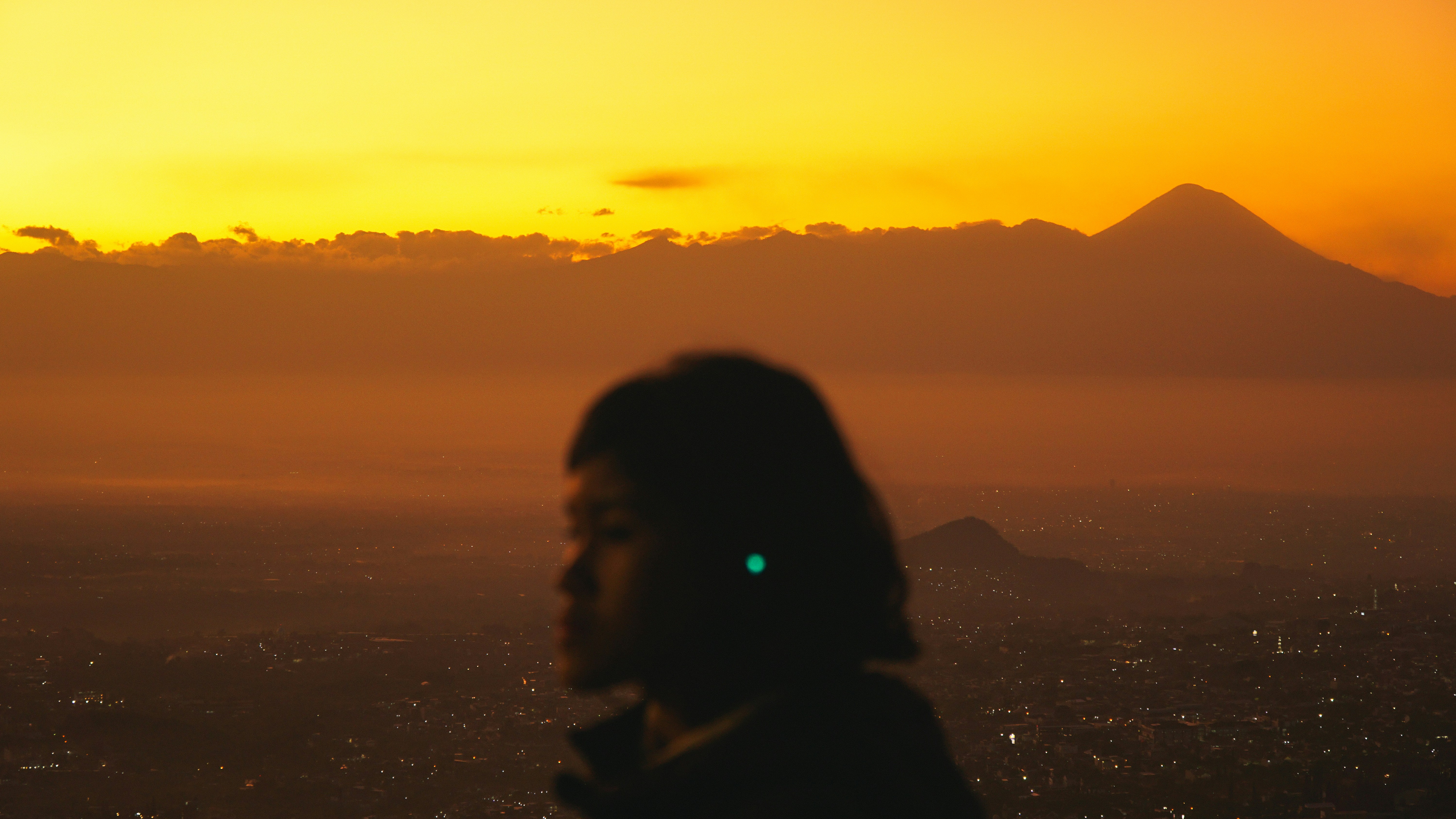 Silhouette of person against vibrant sunset over city