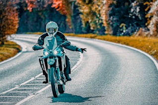 Motorcyclist riding on a winding road in autumn.