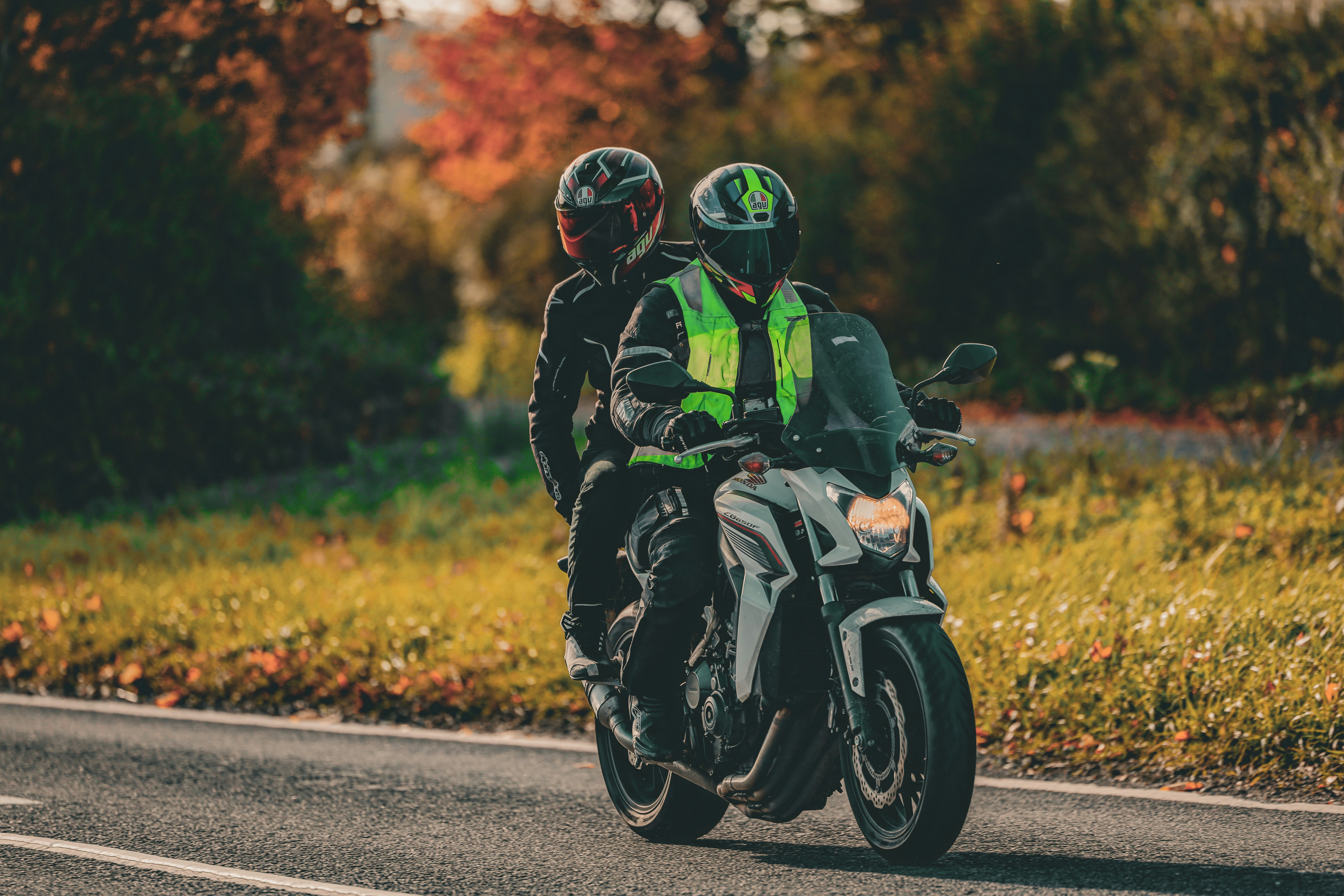 Two people riding a motorcycle on a road