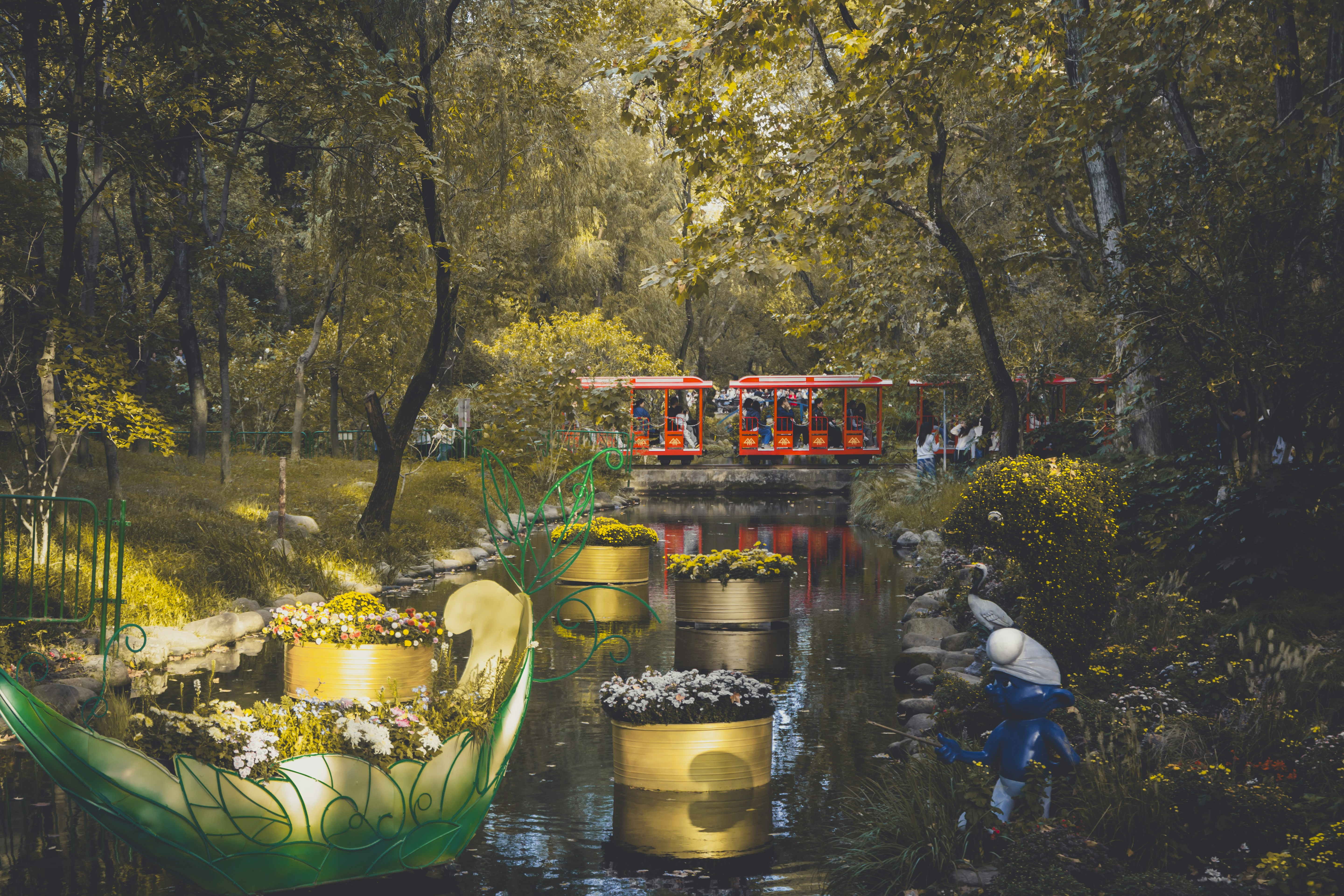 I vagoni del treno rosso attraversano un parco con un canale.
