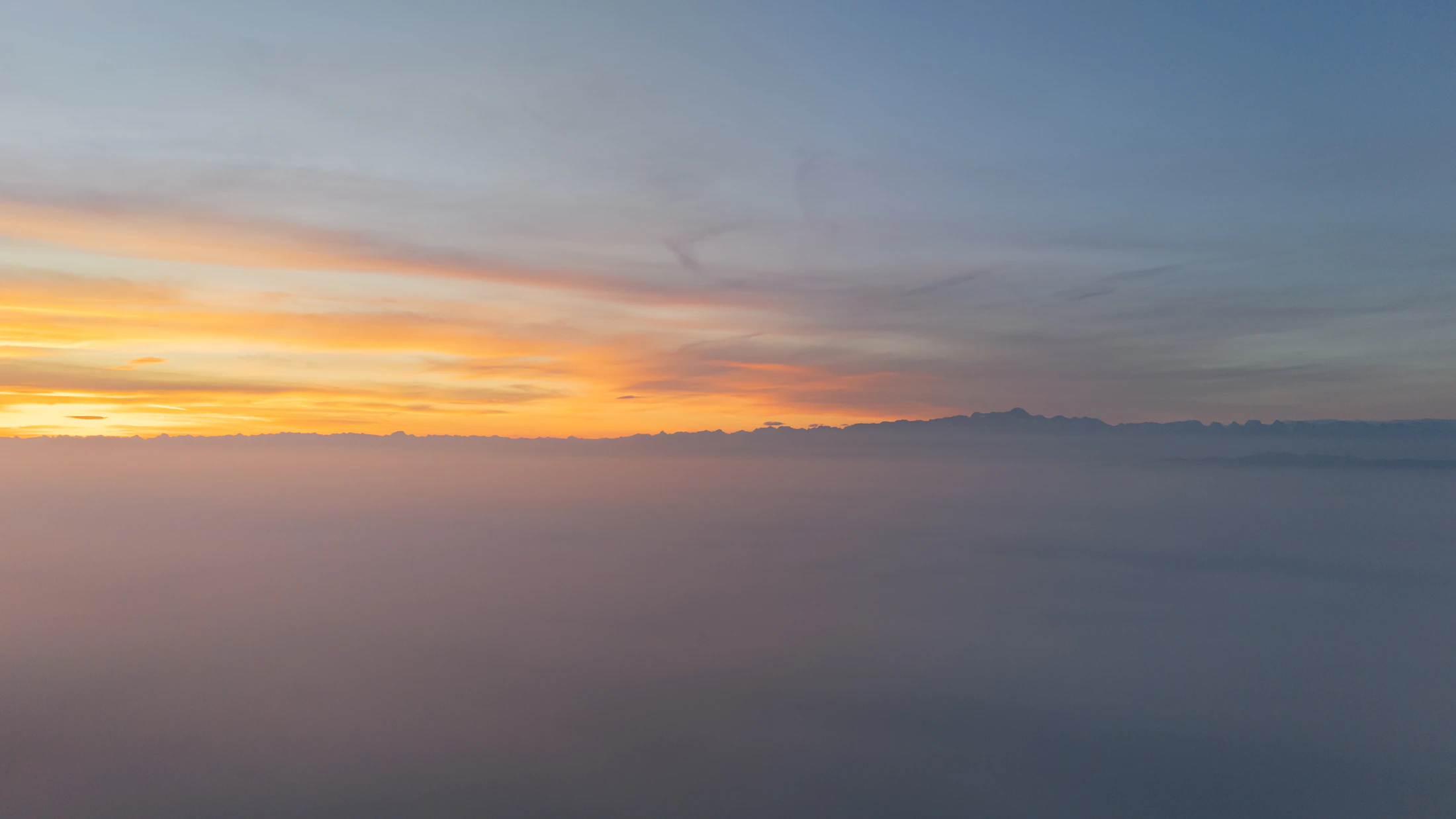Sunrise over a misty mountain range in soft pastel light