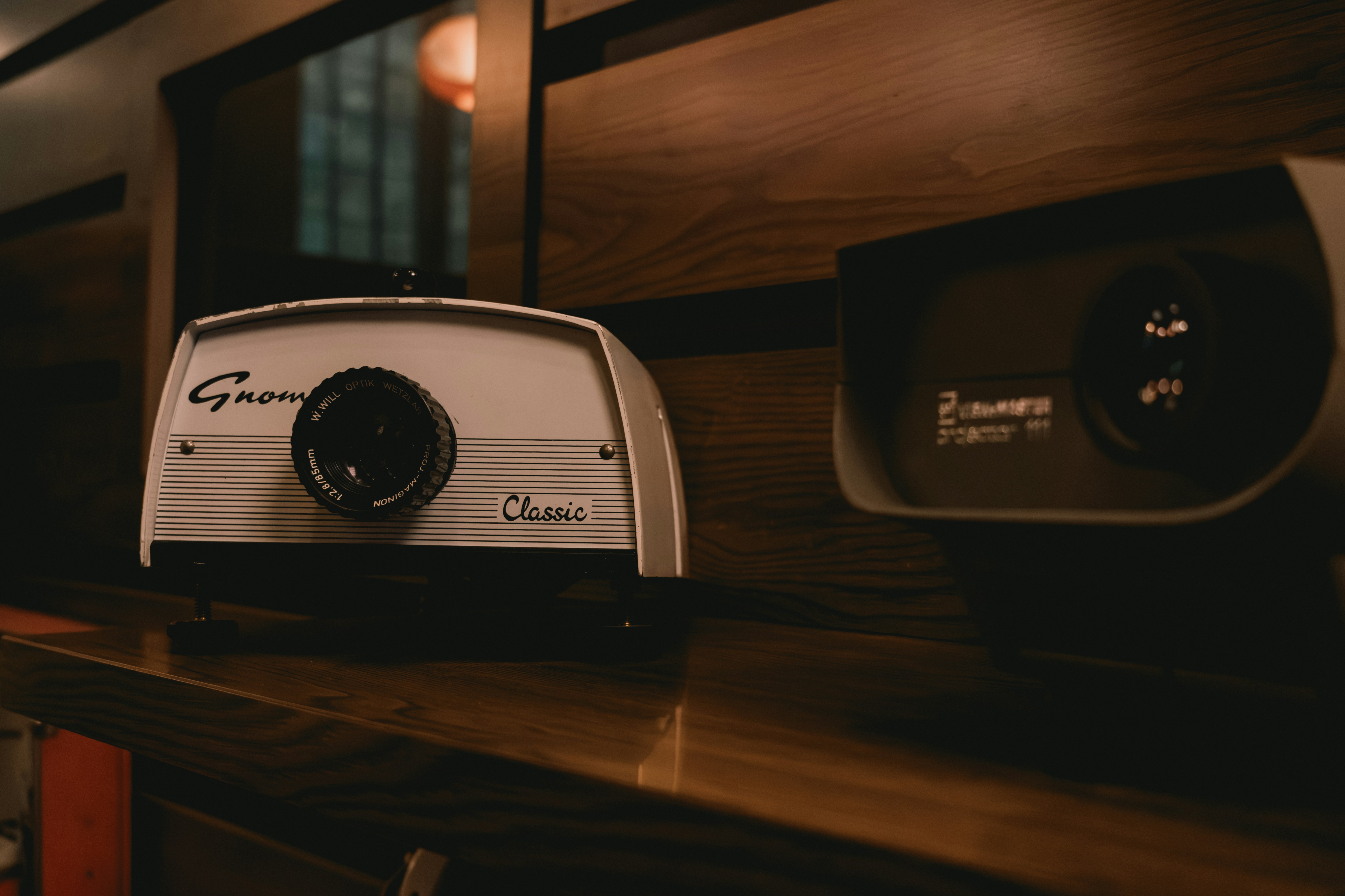 Two vintage projectors on a wooden shelf