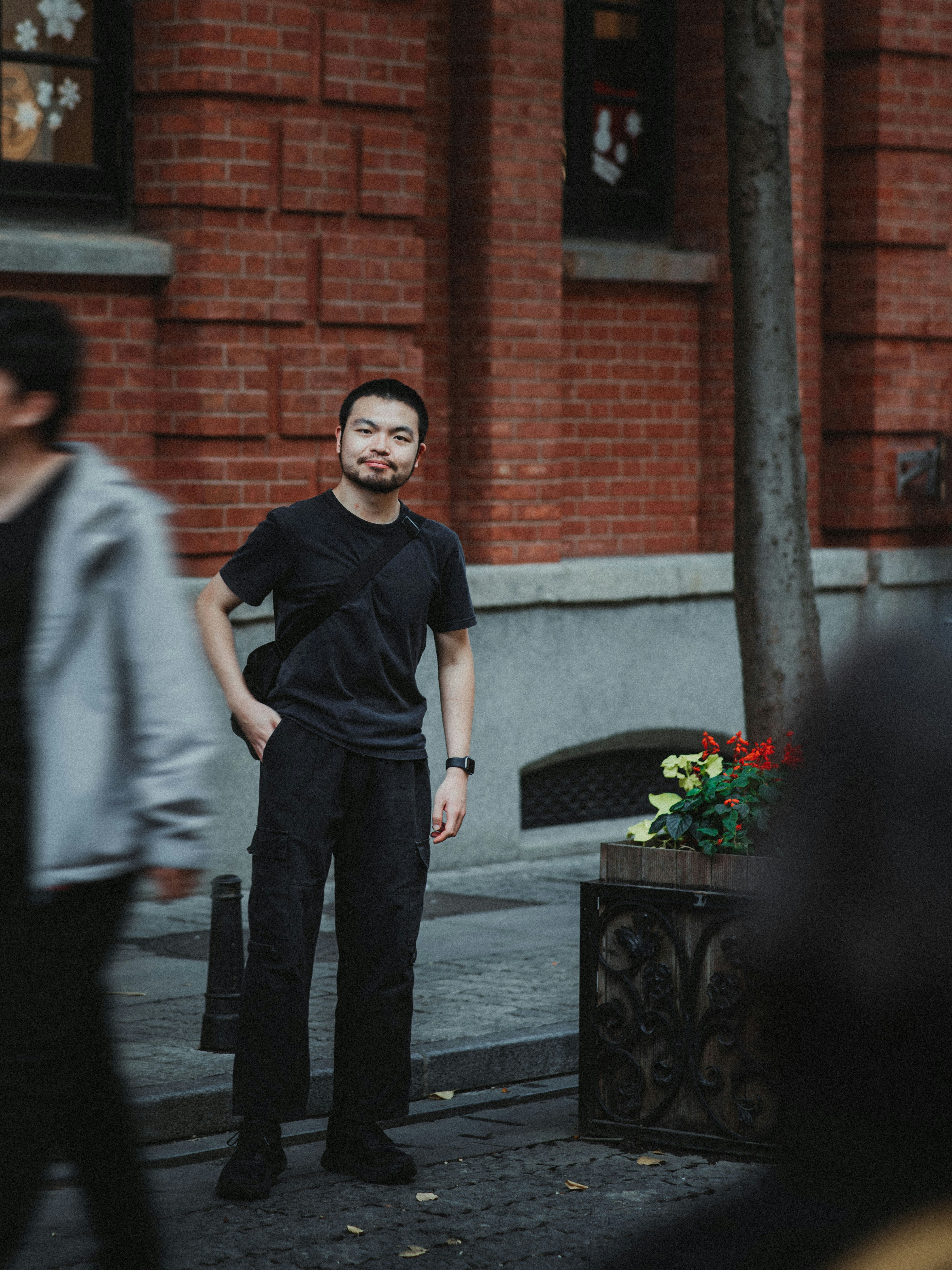 A man in black stands on a city street.