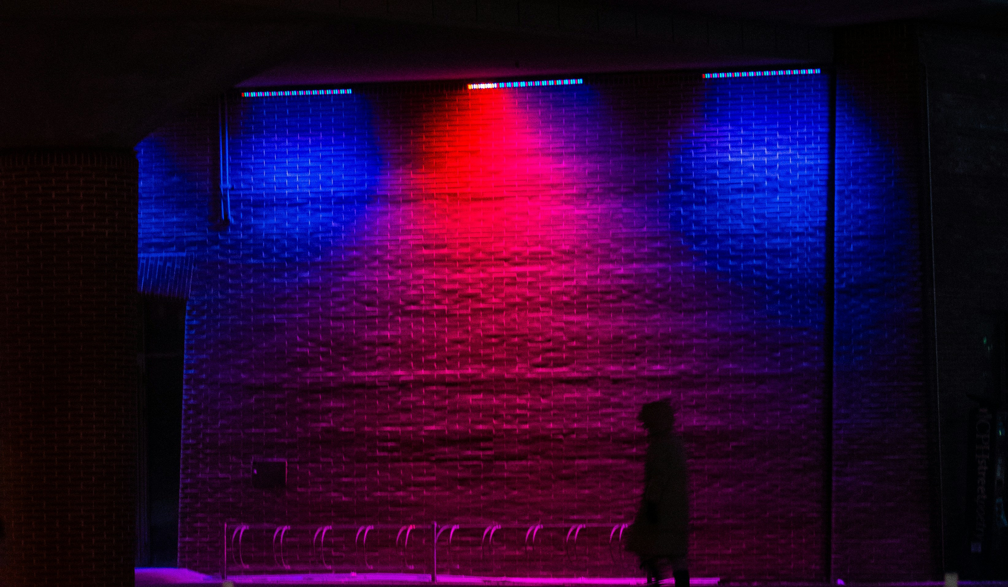 Person standing before a wall with red and blue lights