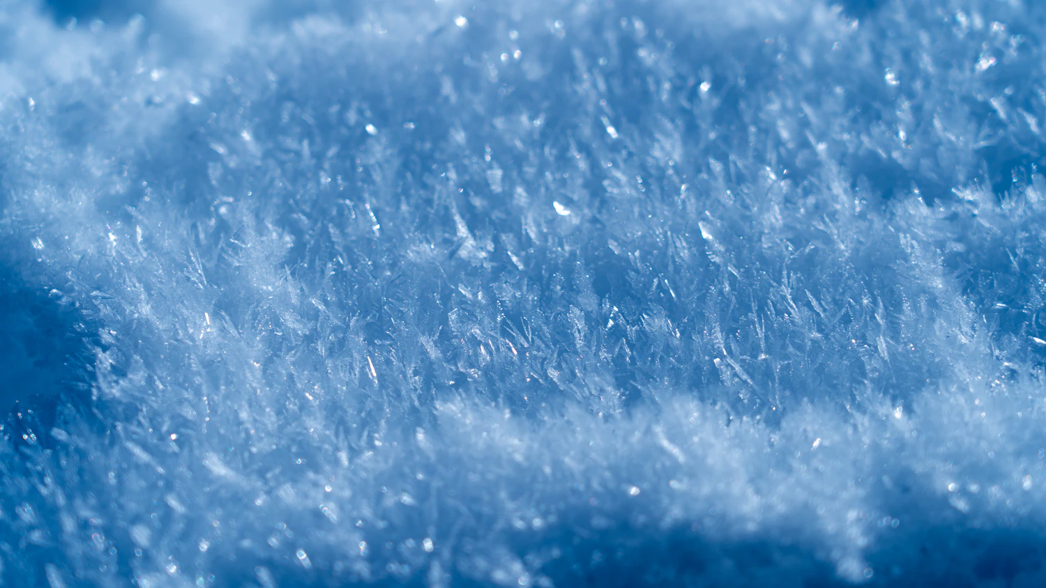 Ice crystals catching light on the surface of packed snow, magnified
