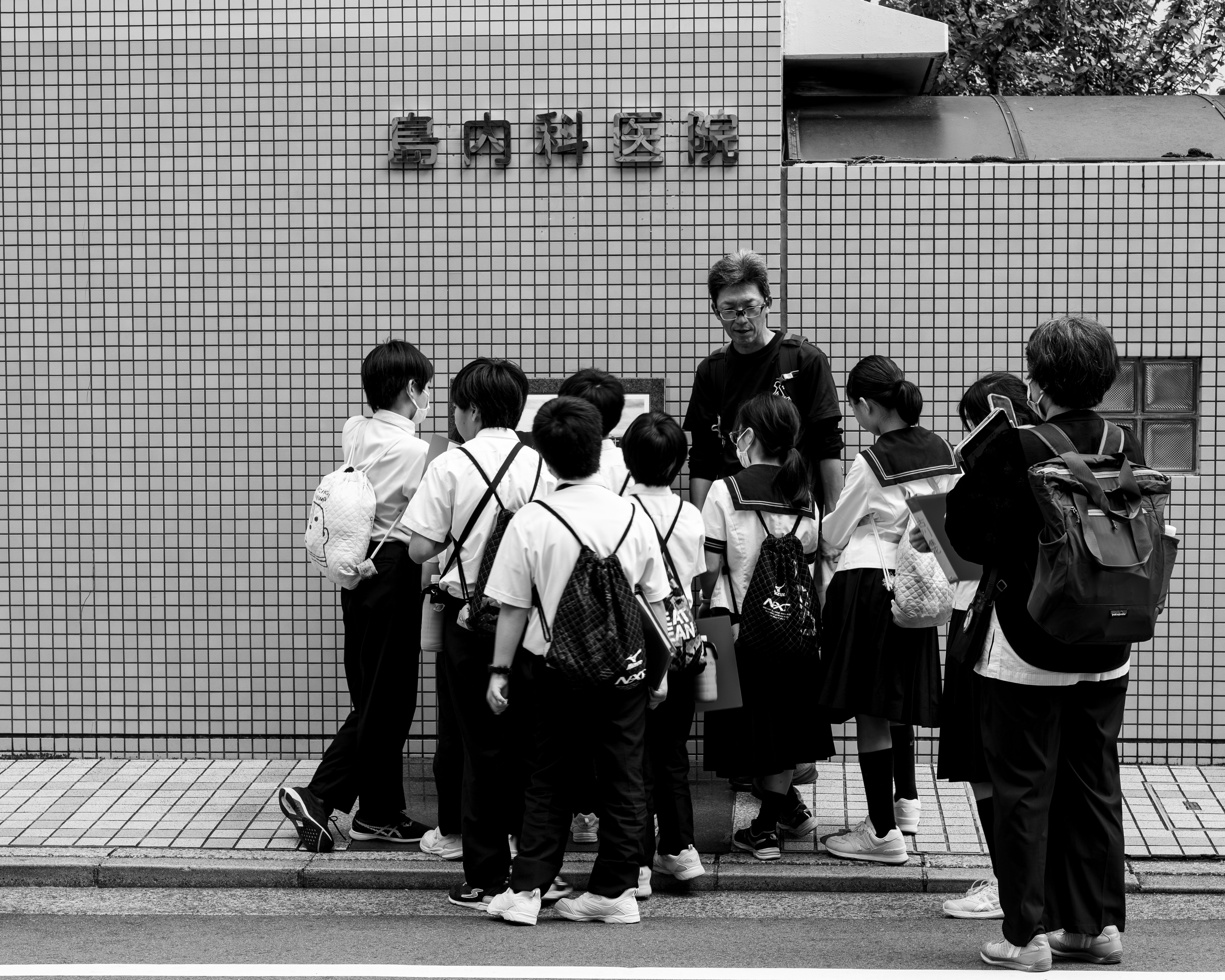 Students gather outside a building with japanese text.