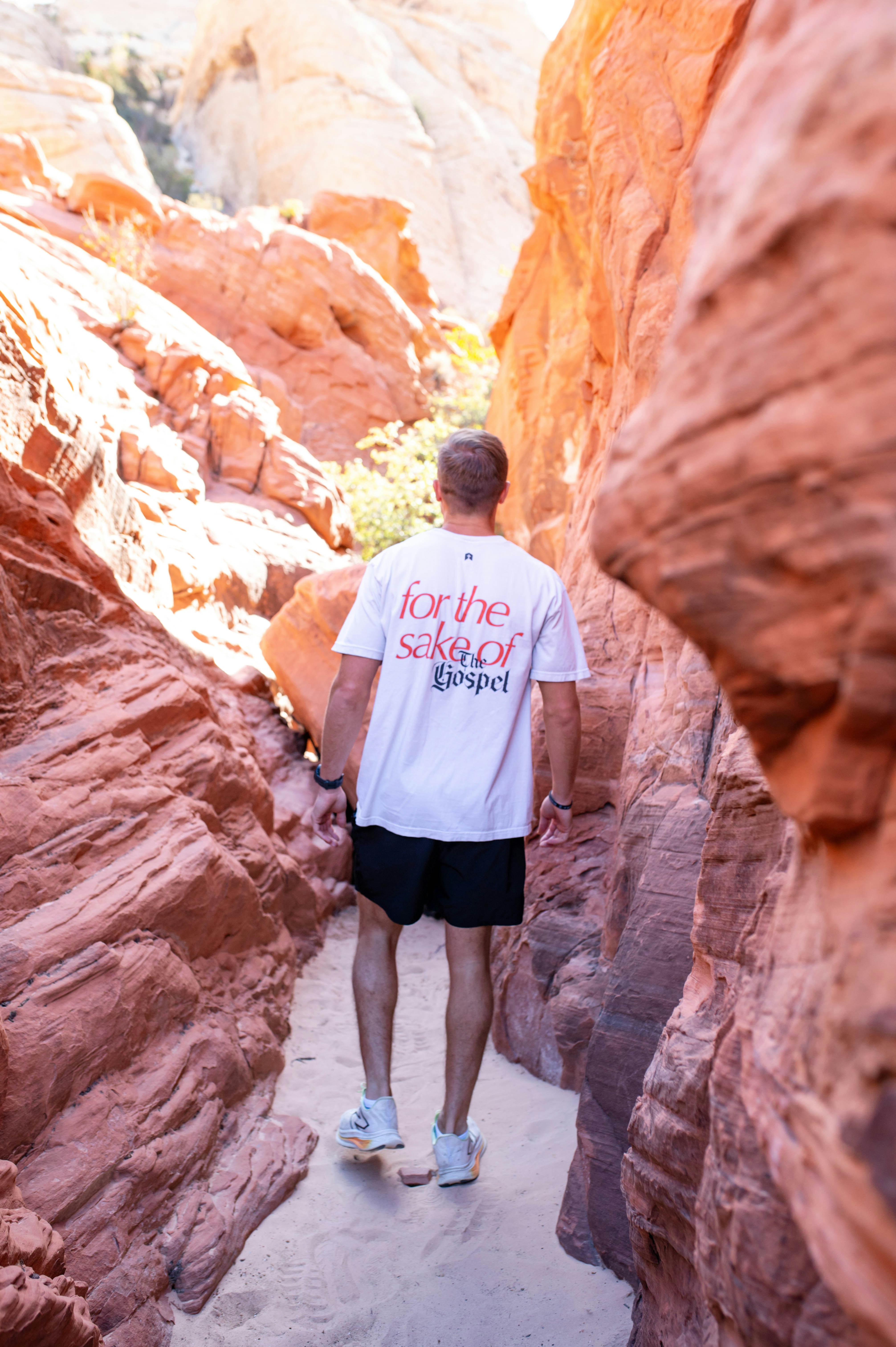Man walks through a narrow desert canyon.