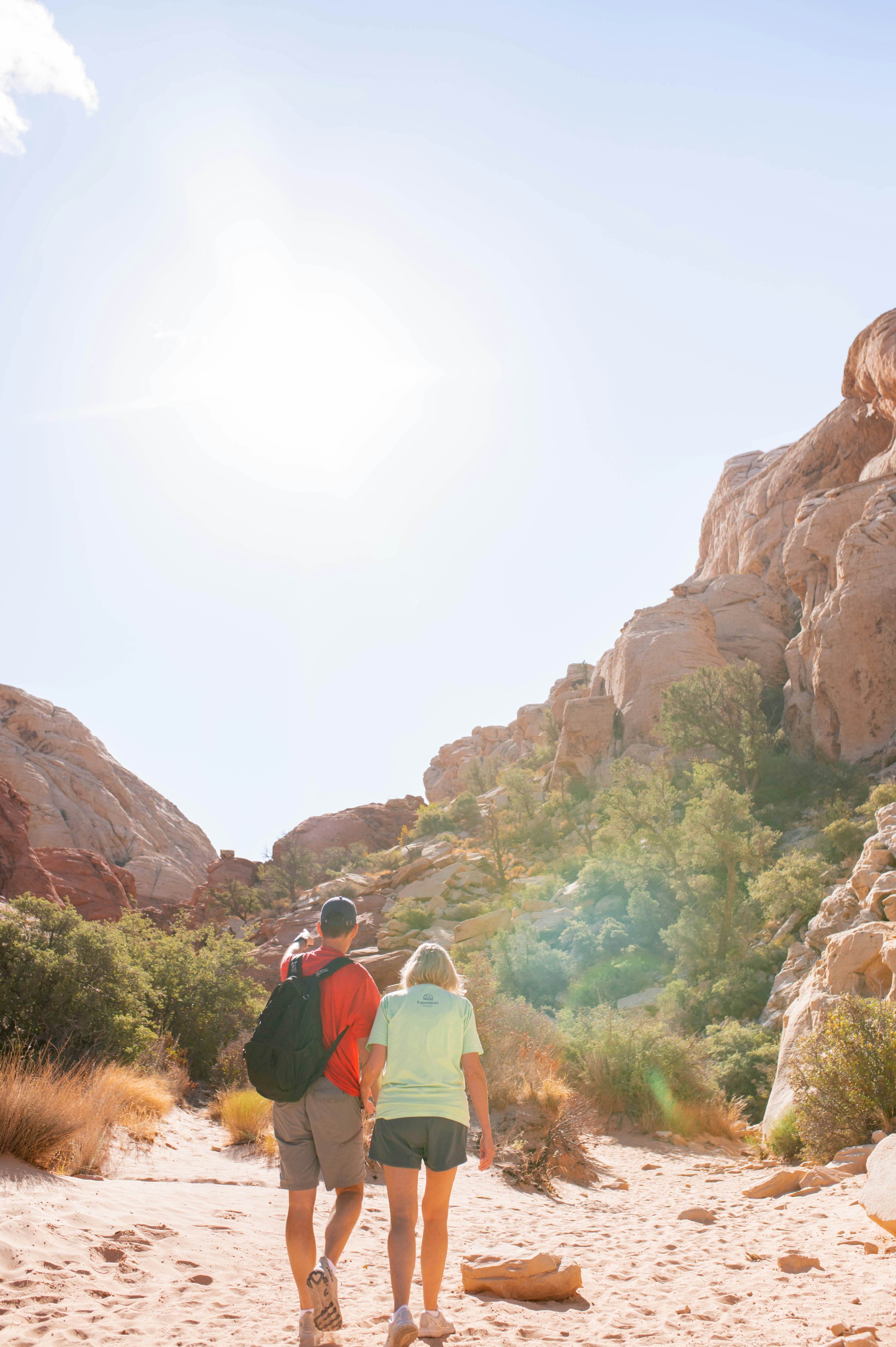 Two hikers walk through a desert canyon