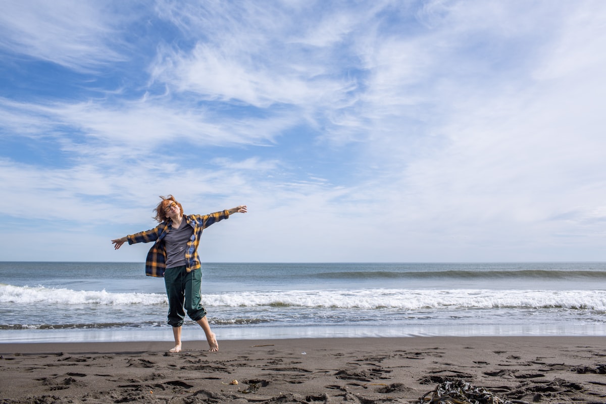 A person jumping joyfully on a sandy beach, the freedom that comes with financial savings