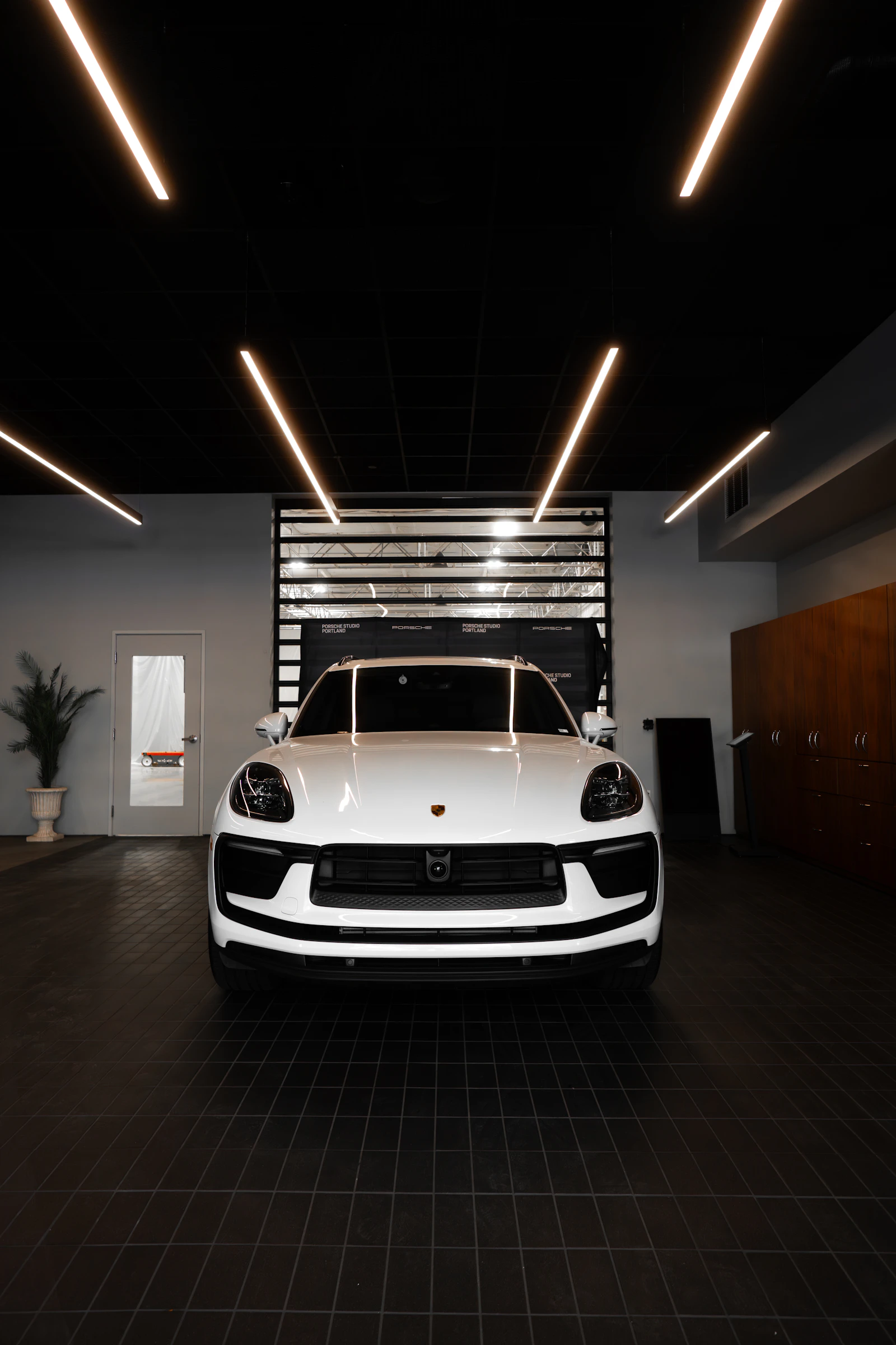 Studio alb, luminos, cu o masina premium in centrul spatiului de lucru