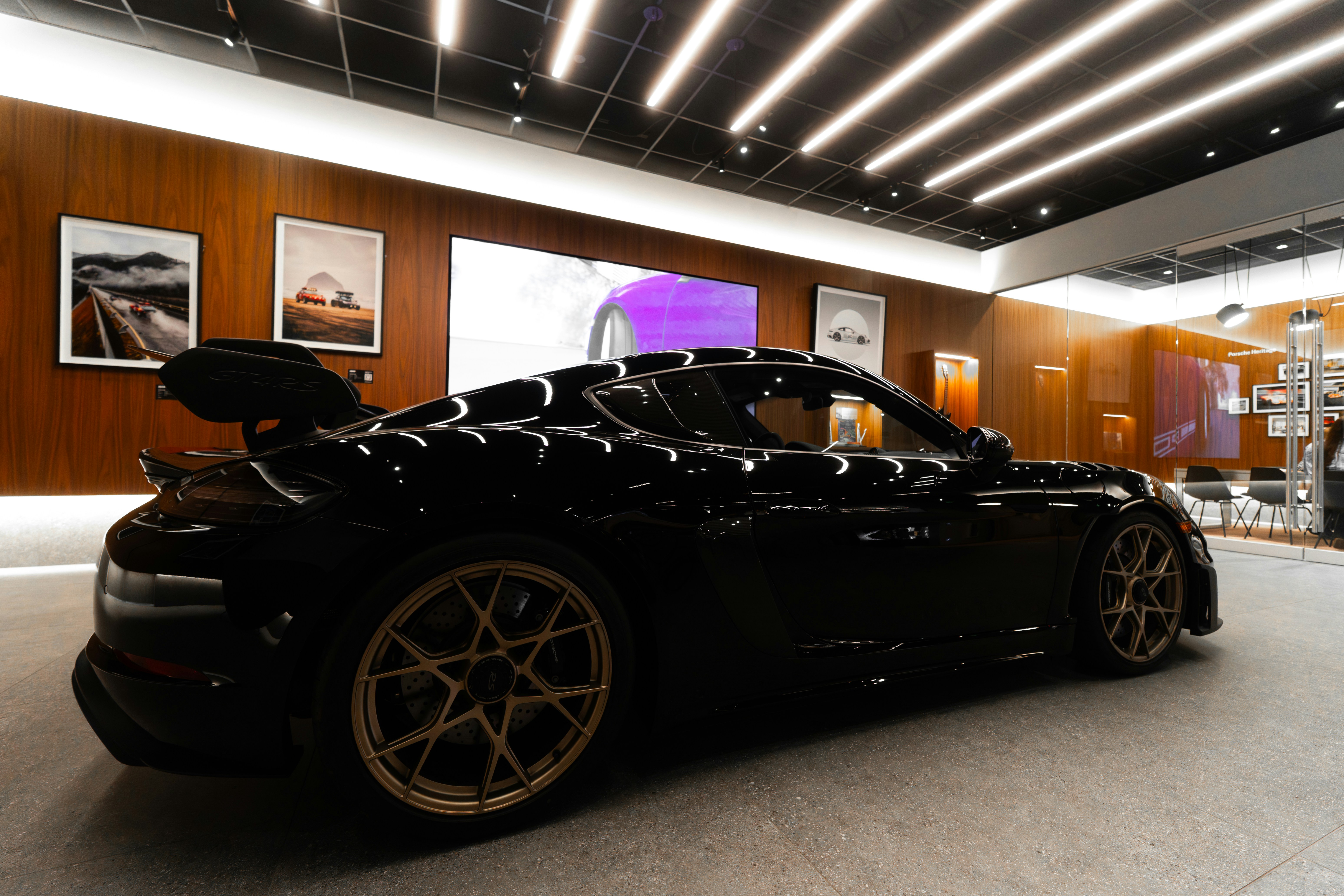 Sleek black sports car with gold wheels indoors