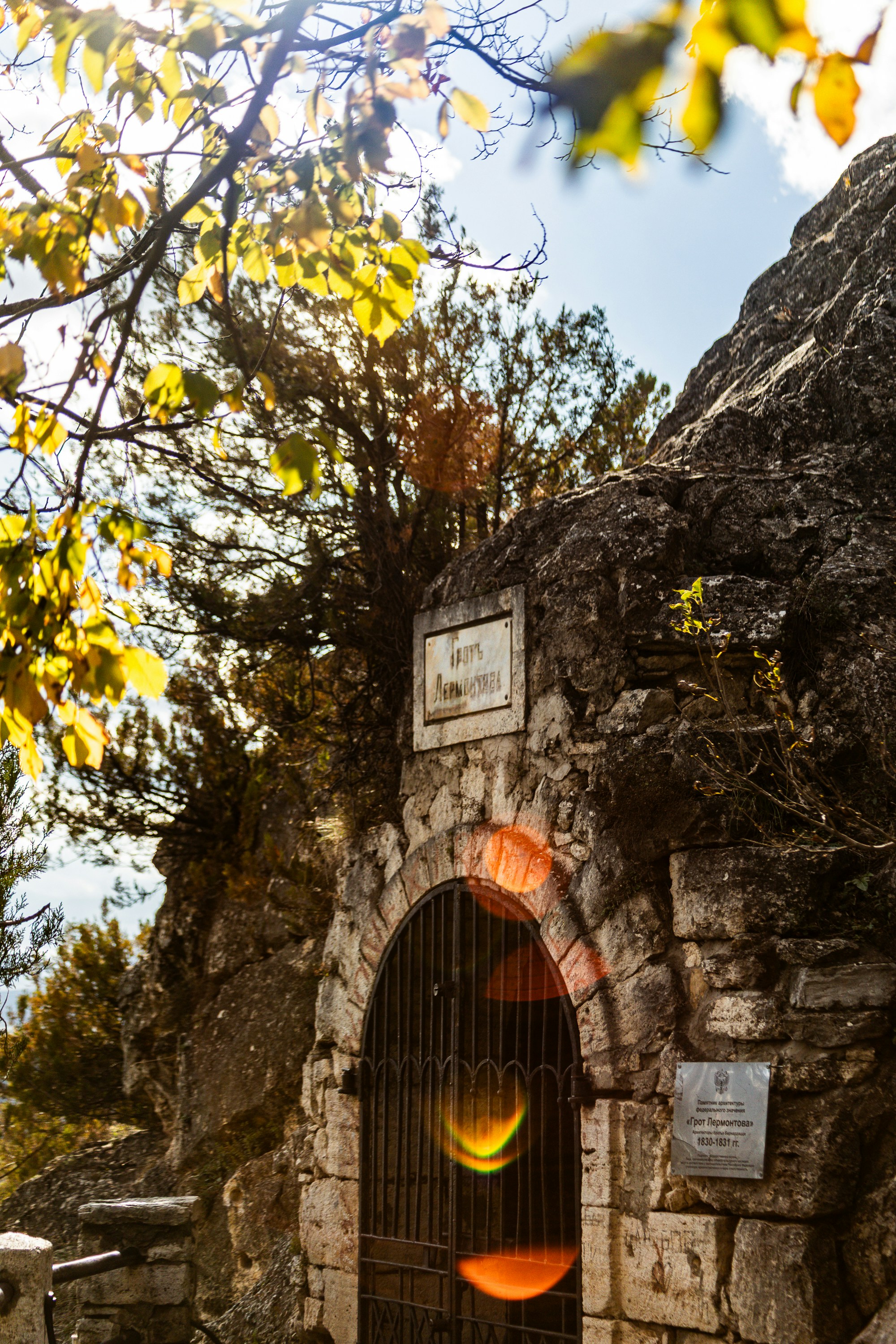 Stone archway with metal gate and autumn leaves