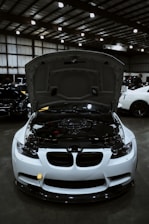 White sports car with hood open showing engine