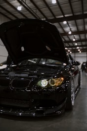 Black car with hood open at indoor event