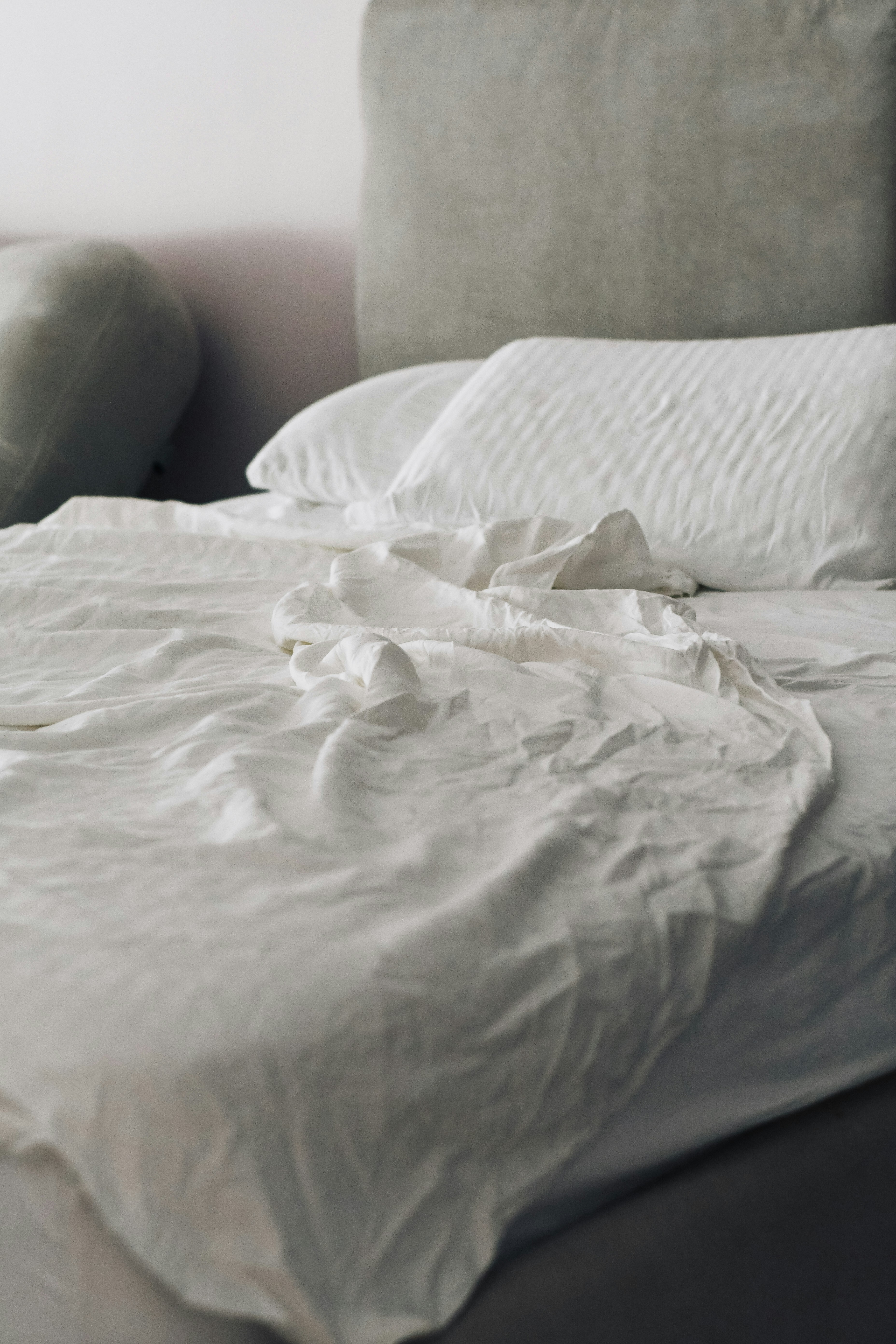 Neatly made bed with white linens and pillows after mattress deep cleaning