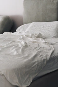 Neatly made bed with white linens and pillows.