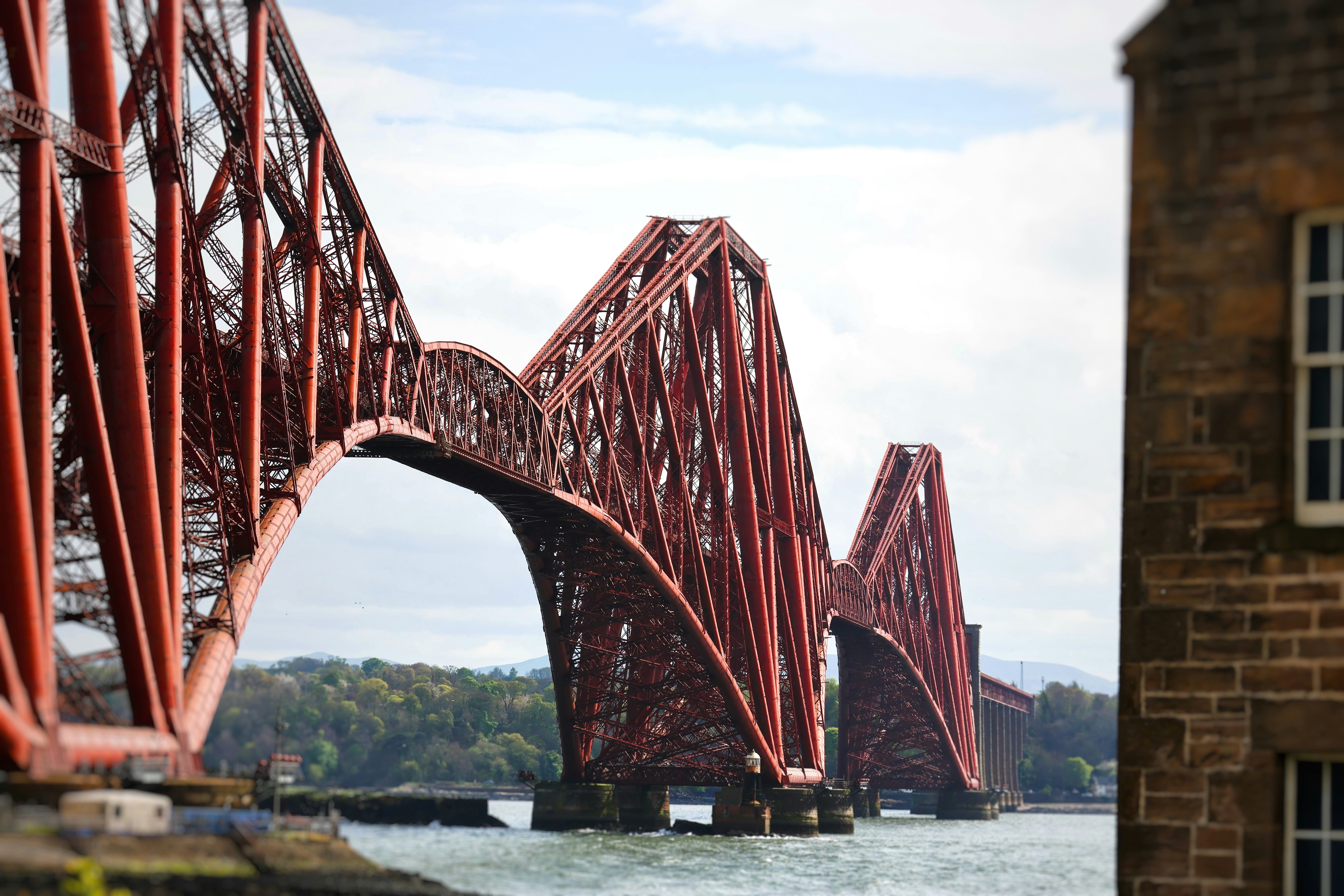 A large red cantilever railway bridge over water.