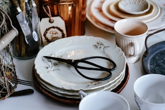 Stack of vintage plates with scissors and copper pot