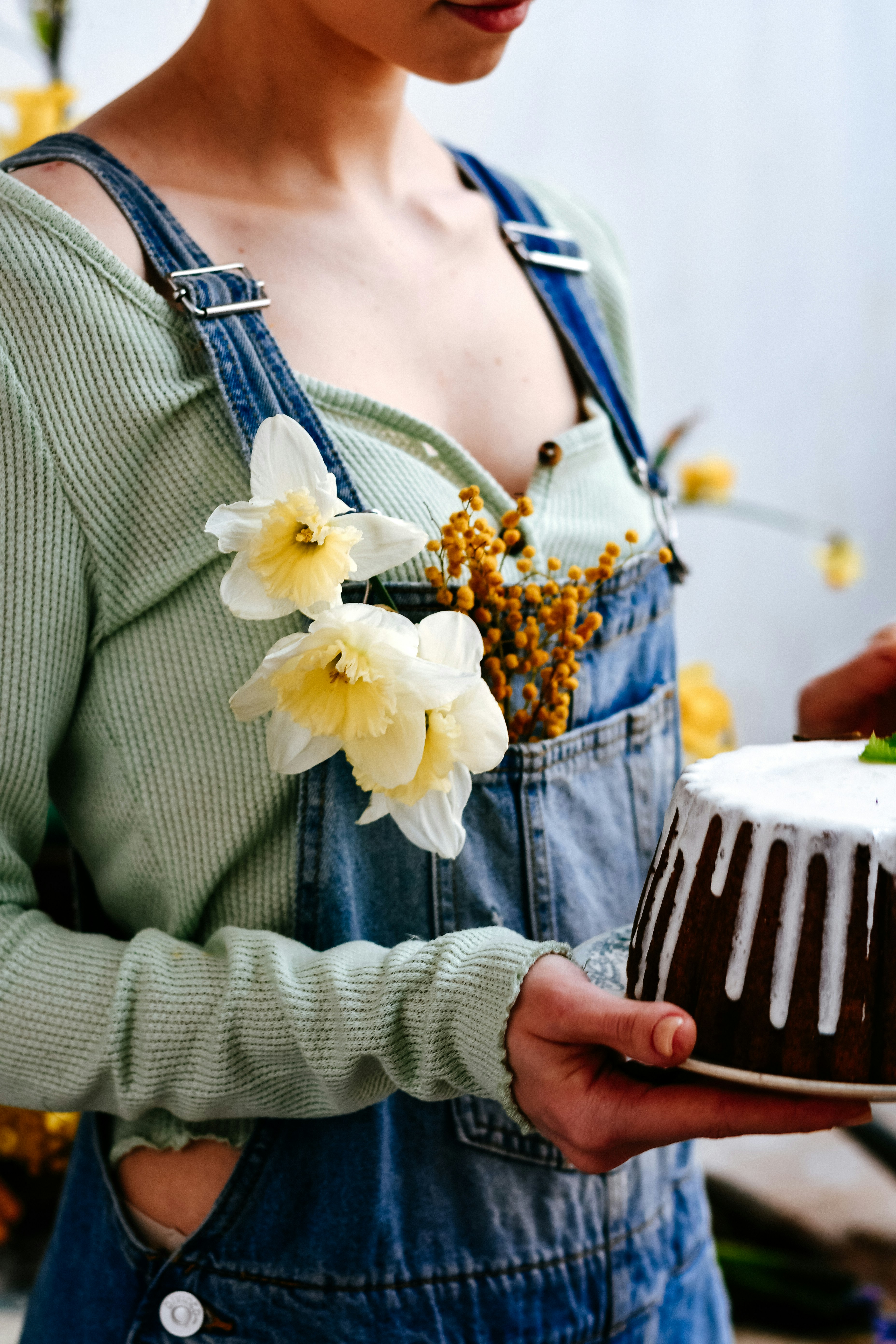 Woman in overalls holding a cake with flowers