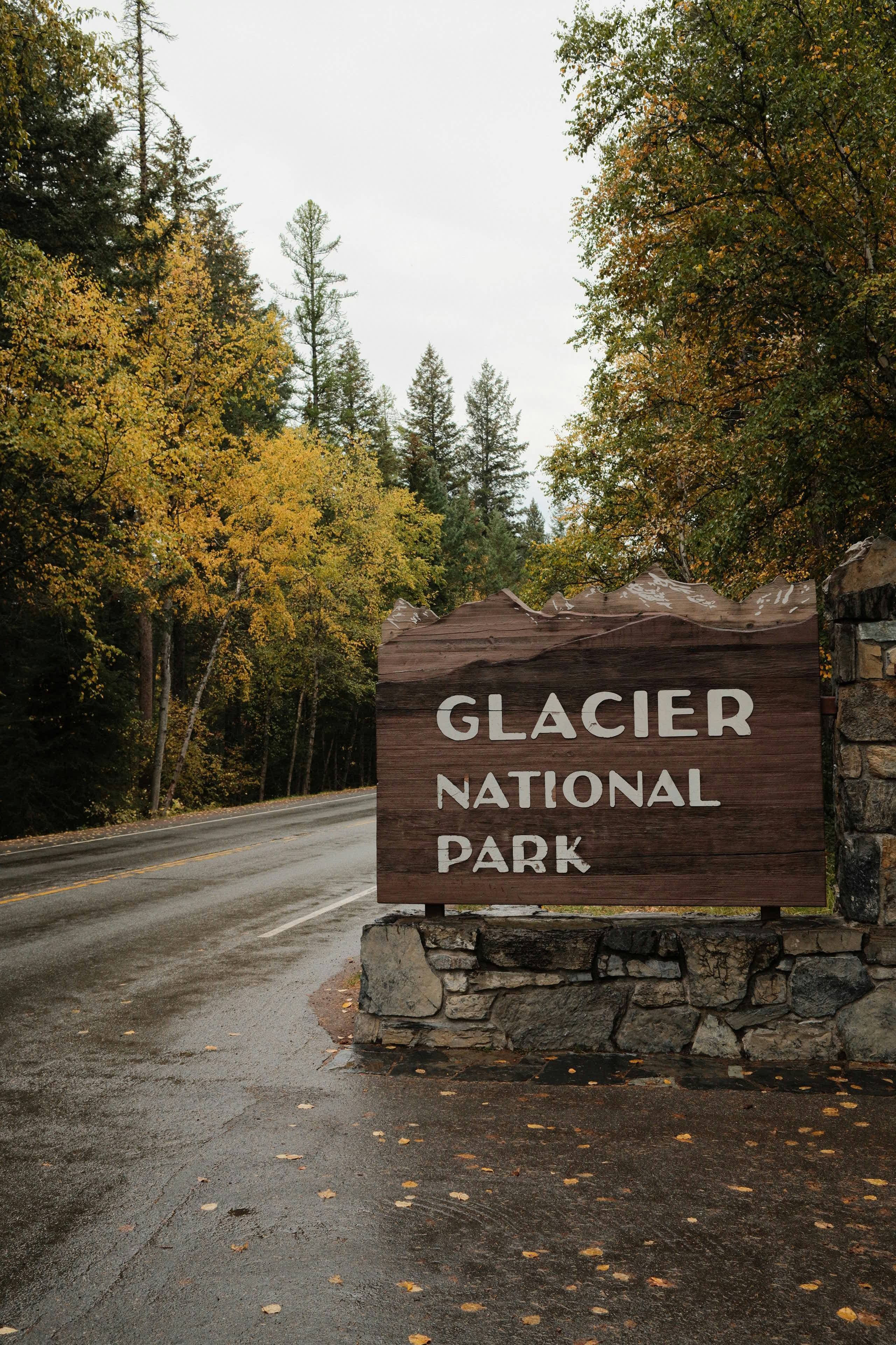 Glacier national park entrance sign with autumn trees.