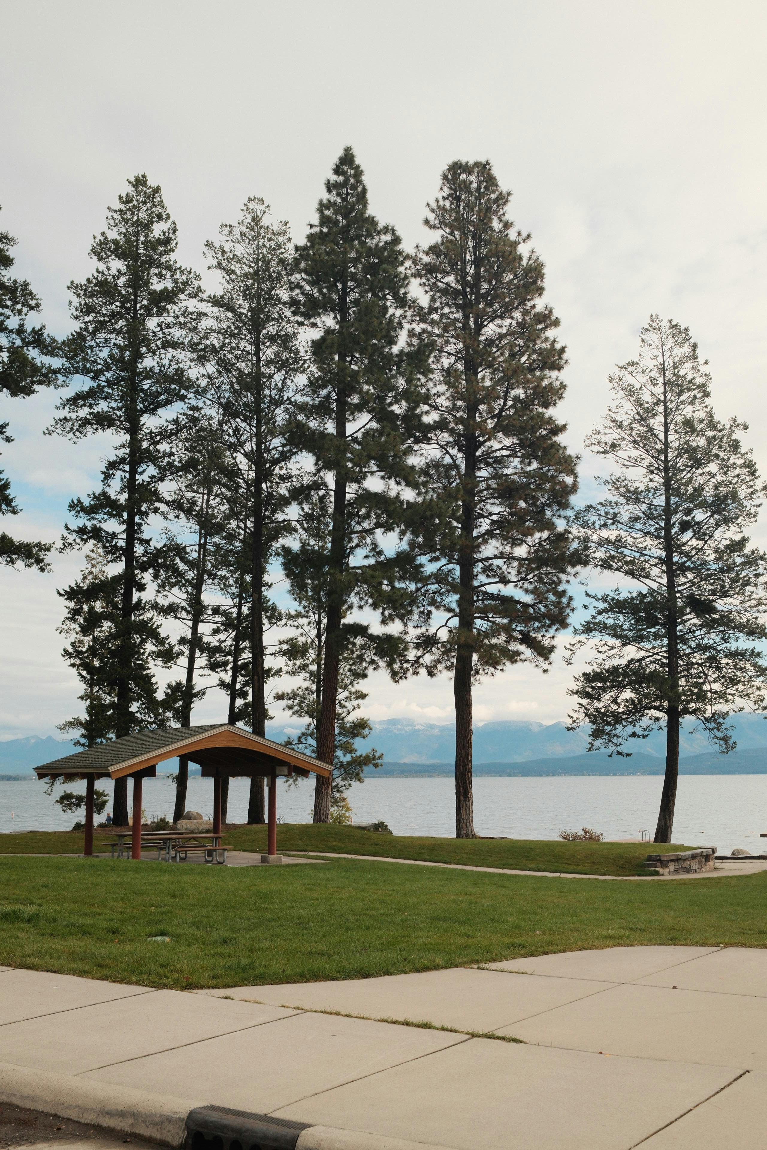 Picnic shelter by a lake with distant mountains.