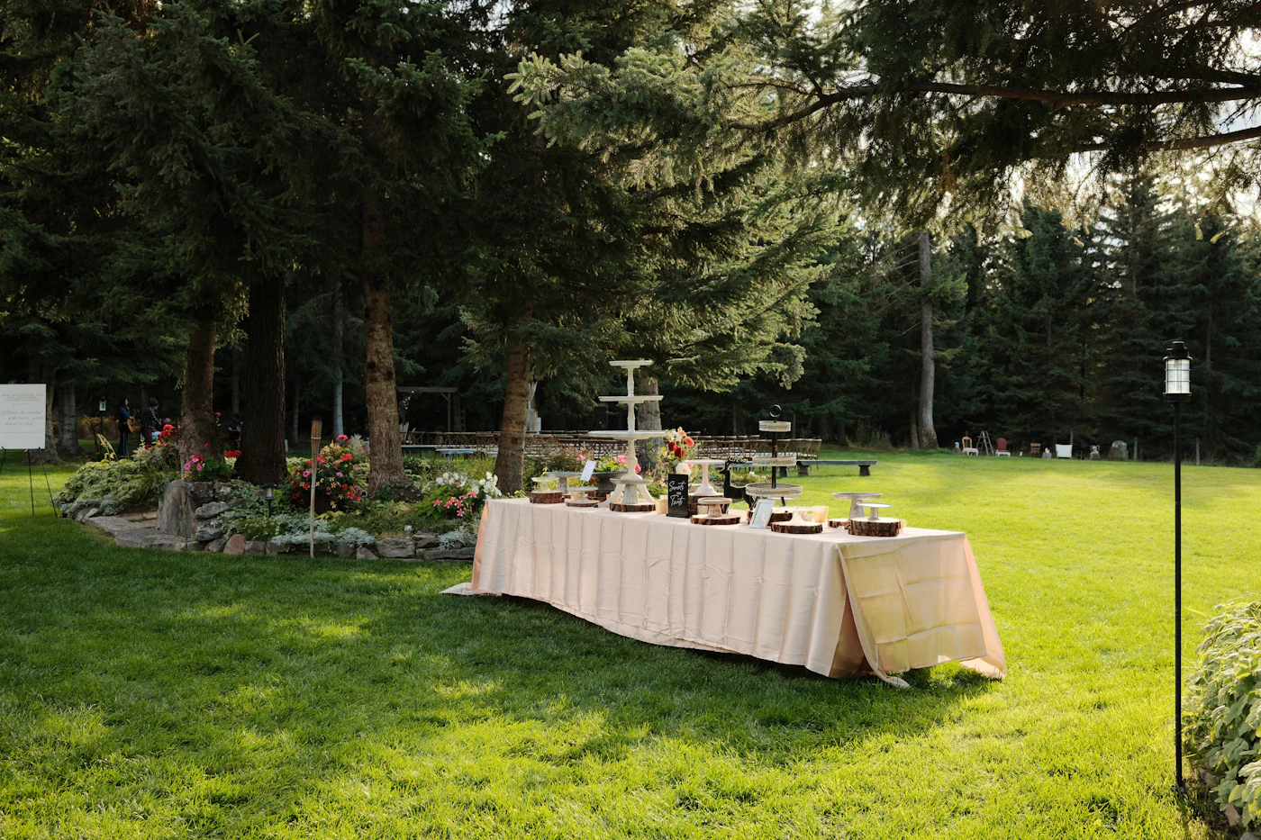 An outdoor wedding banquet table set with elegant place settings floral arrangements and decorative elements for a formal destination wedding reception dinner in a garden setting