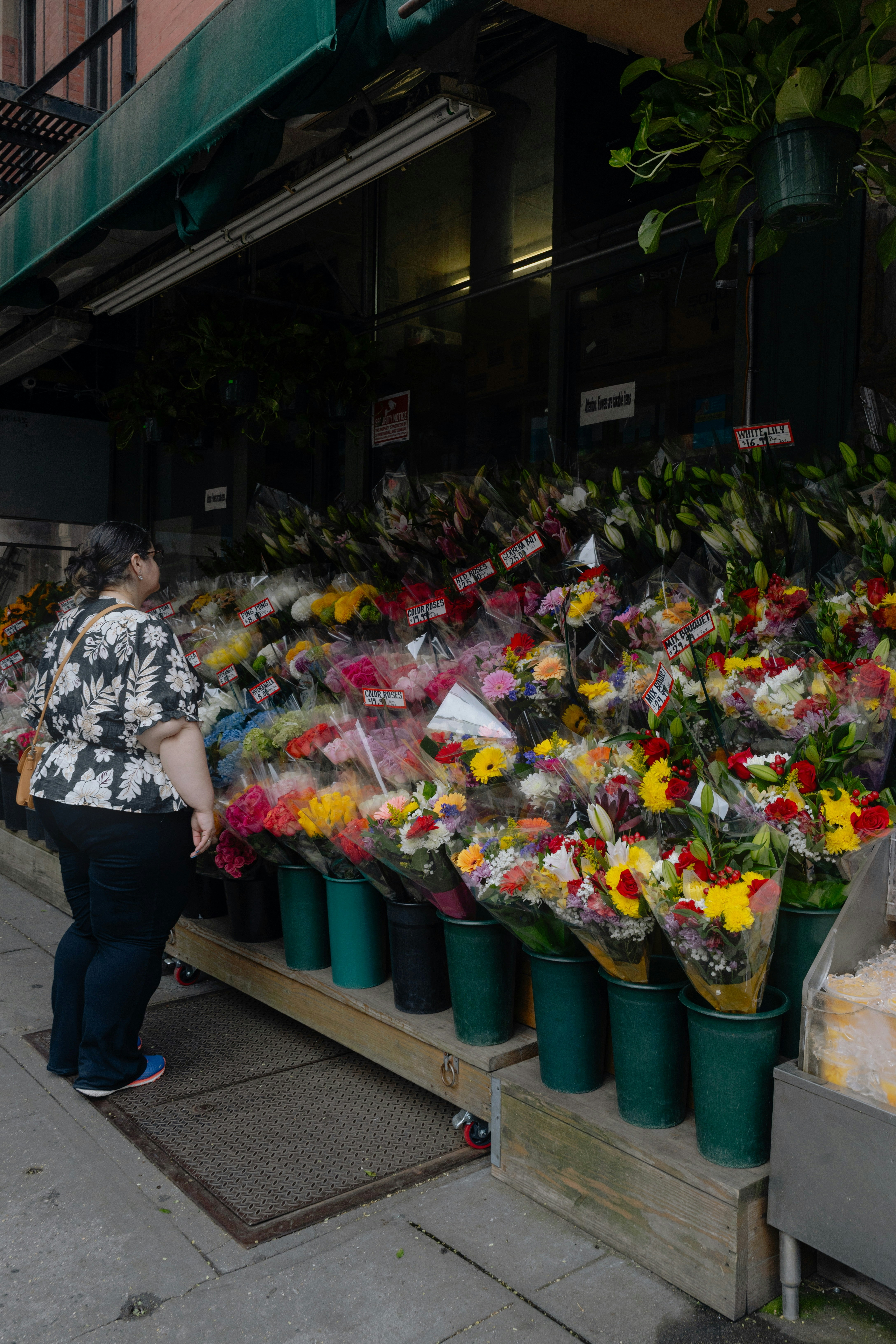 Woman browsing flowers at an outdoor market stall.