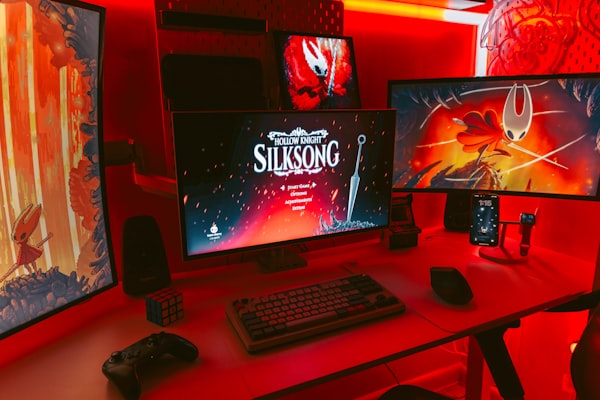 Gaming setup with multiple monitors displaying game art.